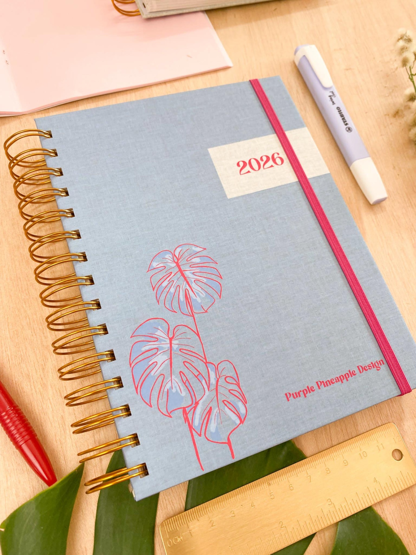 Agenda anual 2026 azul com ilustração e texto Purple Pineapple Design