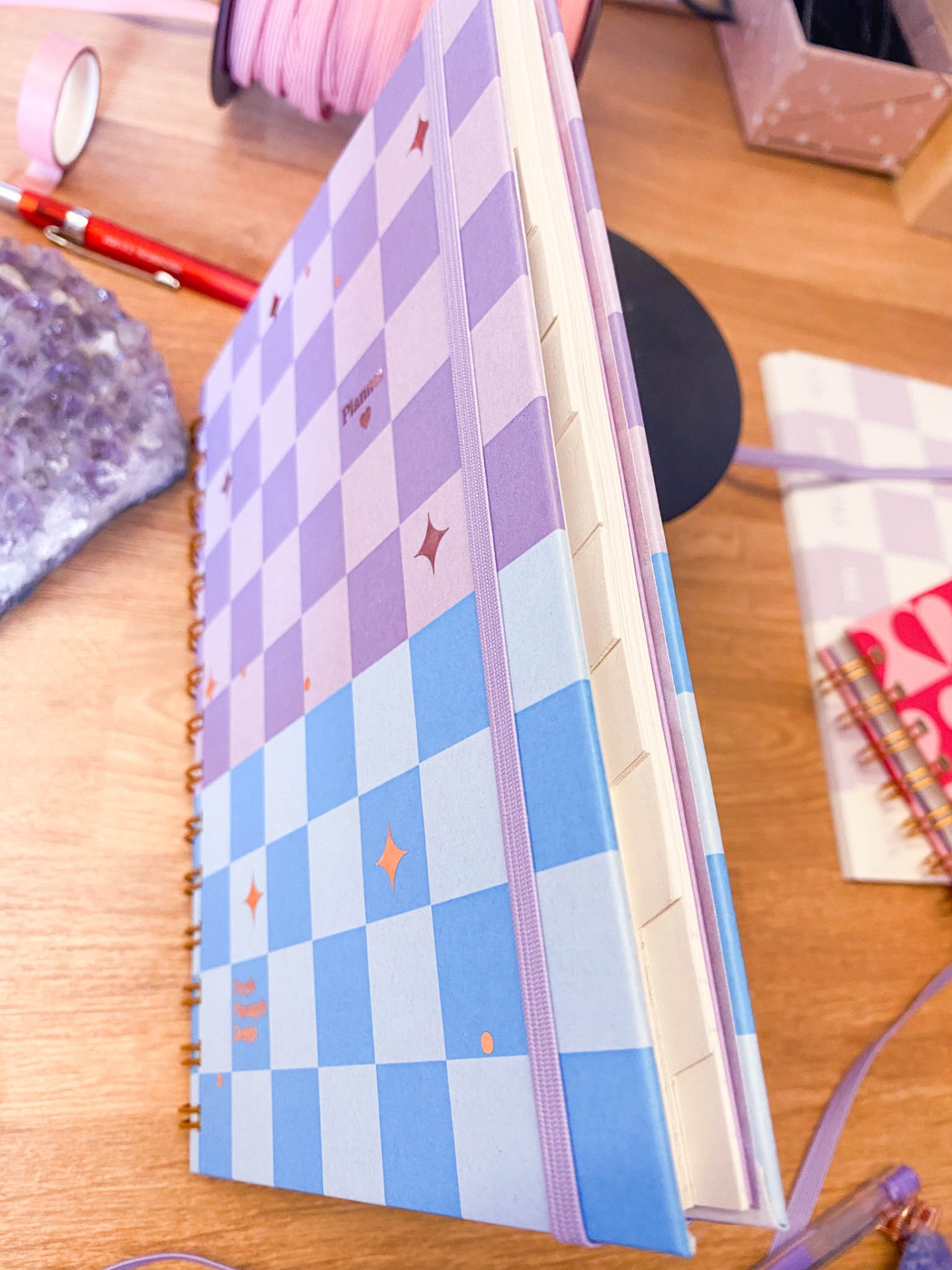 Caderno espiral azul e lilás com padrão xadrez e elástico lilás
