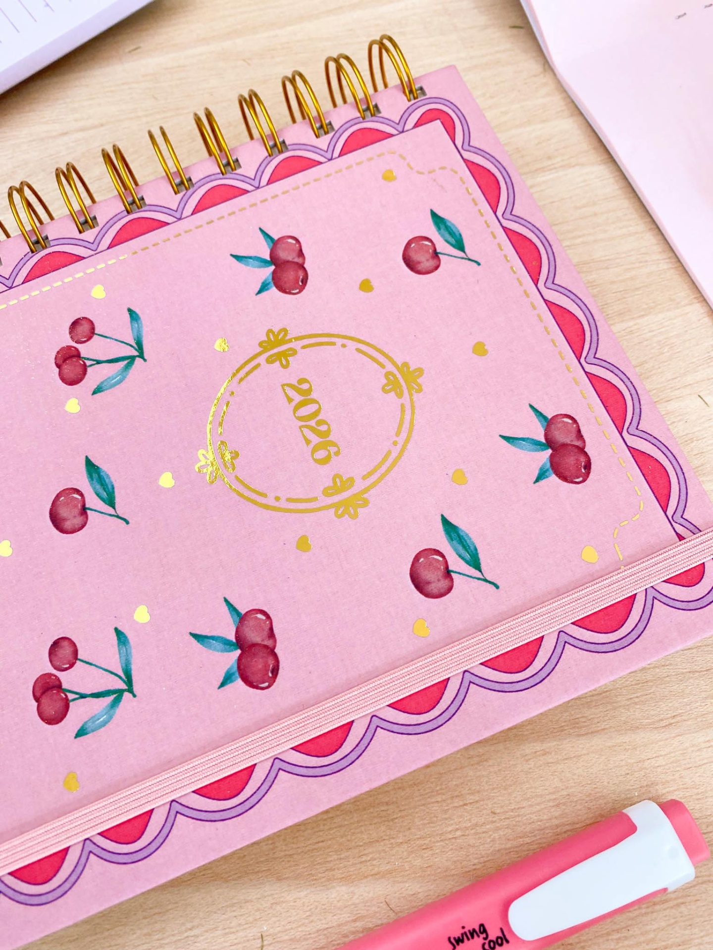 Agenda anual de 2026 rosa com cerejas e detalhes dourados