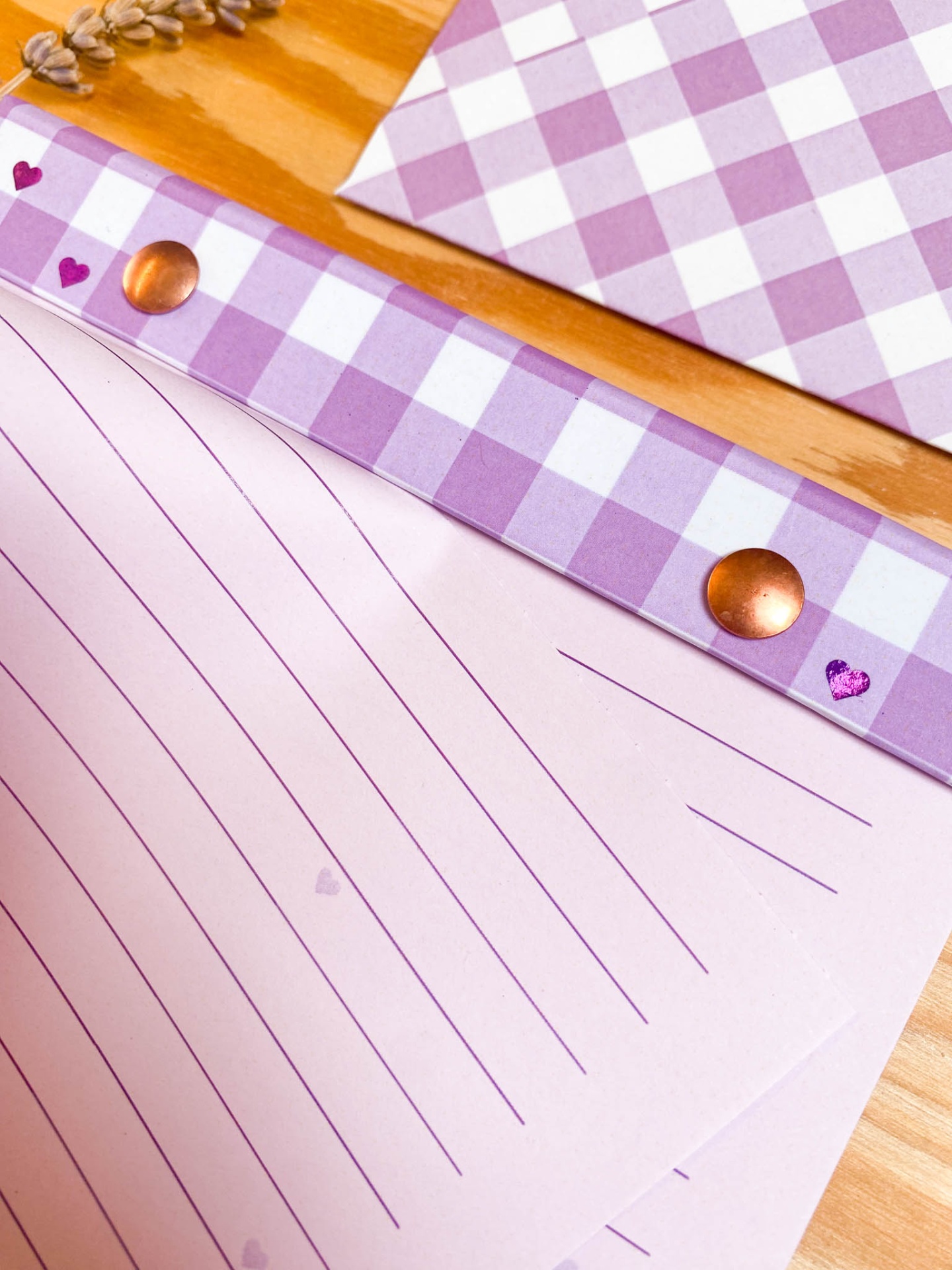 Bloco de notas xadrez lilás com corações em fundo de madeira clara