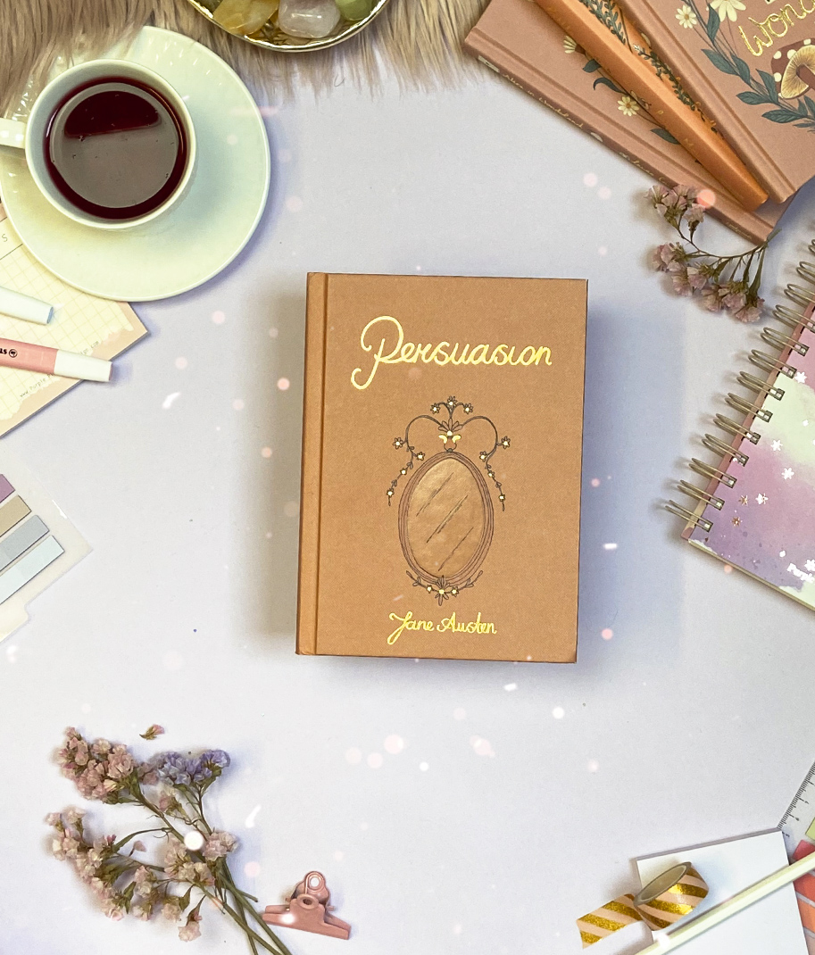 Livro Persuasion de Jane Austen com chá e material de escrita num fundo branco