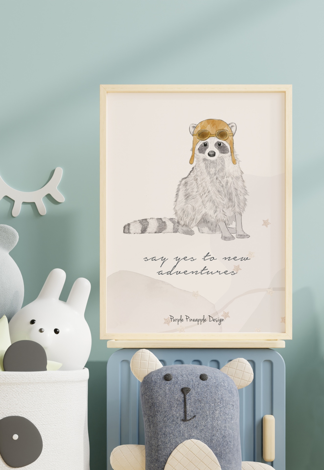 Quadro com ilustração de guaxinim e texto motivacional numa parede azul rodeado de brinquedos de peluche.