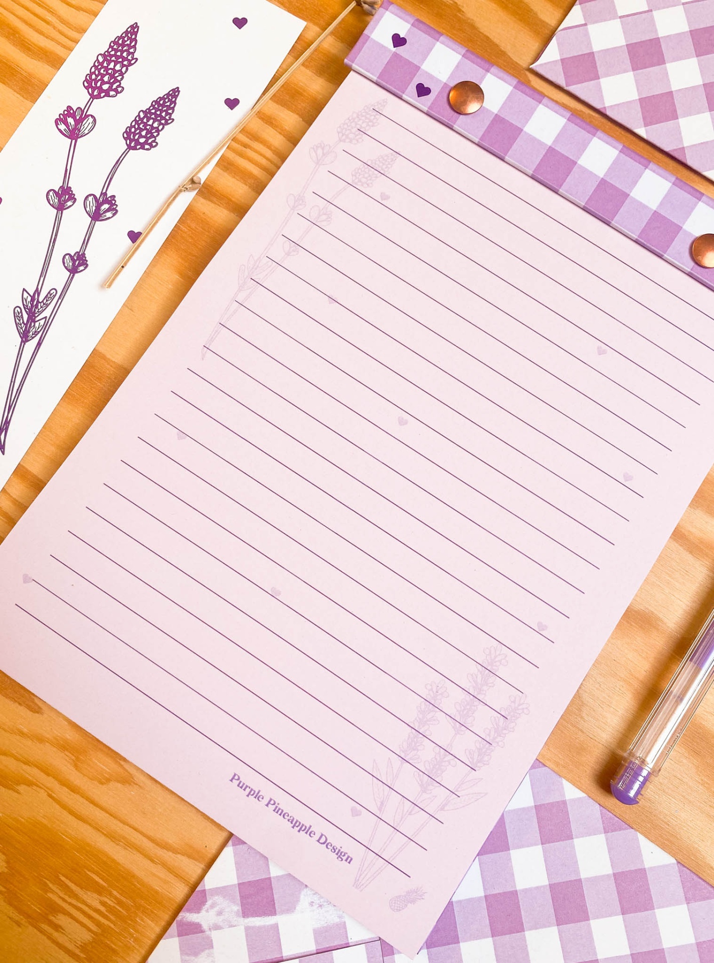 Mesa de madeira com papel pautado rosa e padrão xadrez lilás