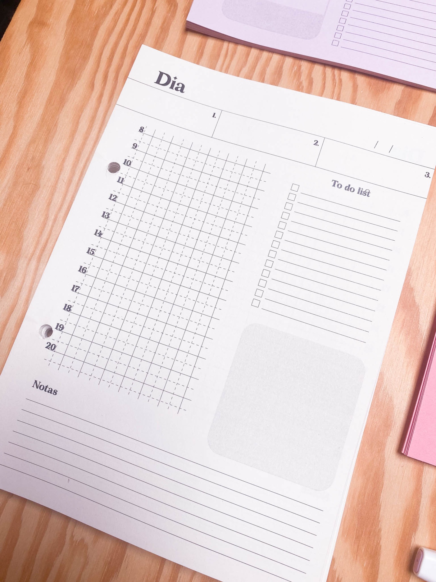 Folha de planeamento diário com horários e secções para tarefas e notas sobre mesa de madeira