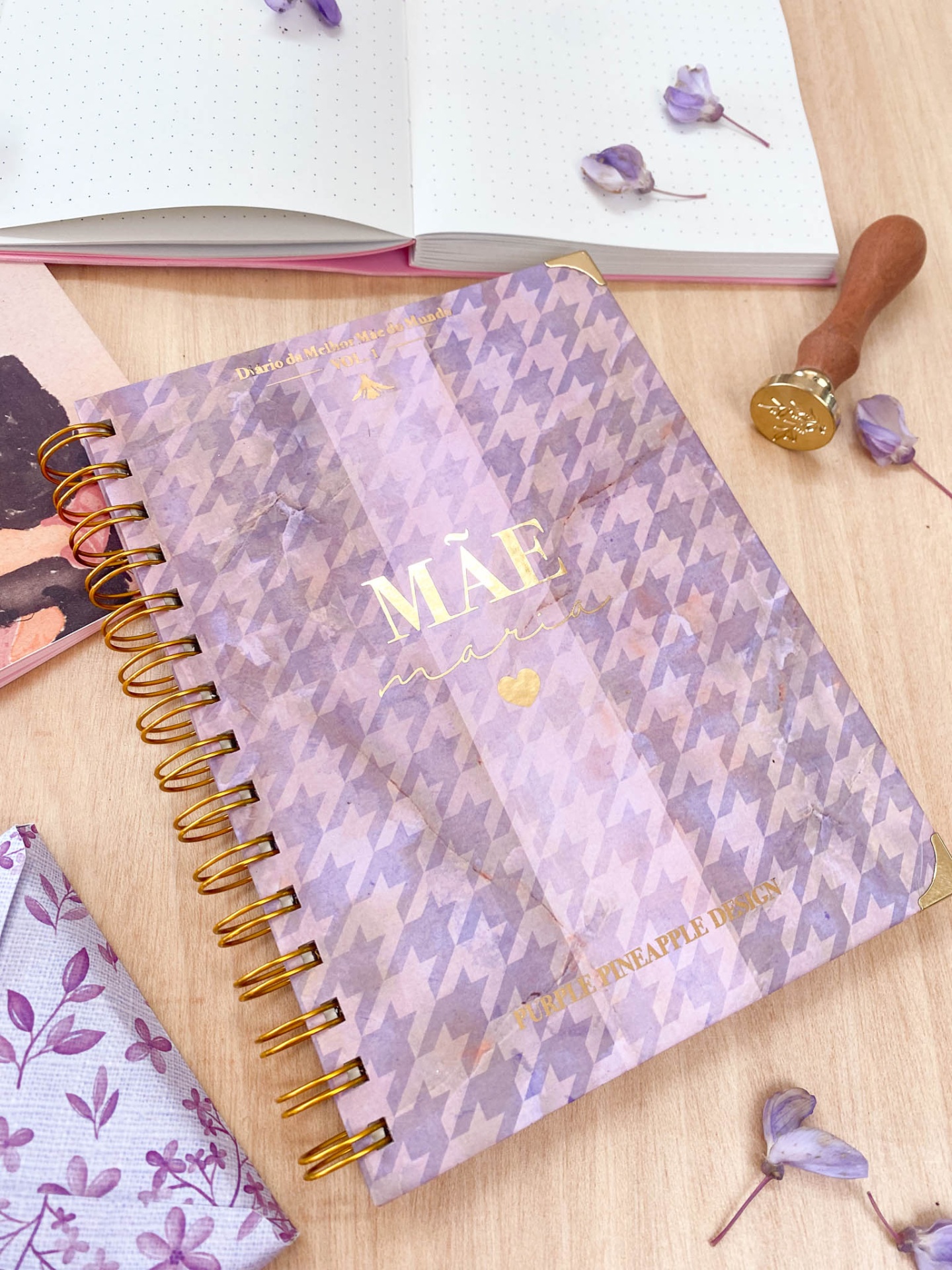 Caderno espiral lilás com padrão pied-de-poule e texto dourado 'MÃE mágica'