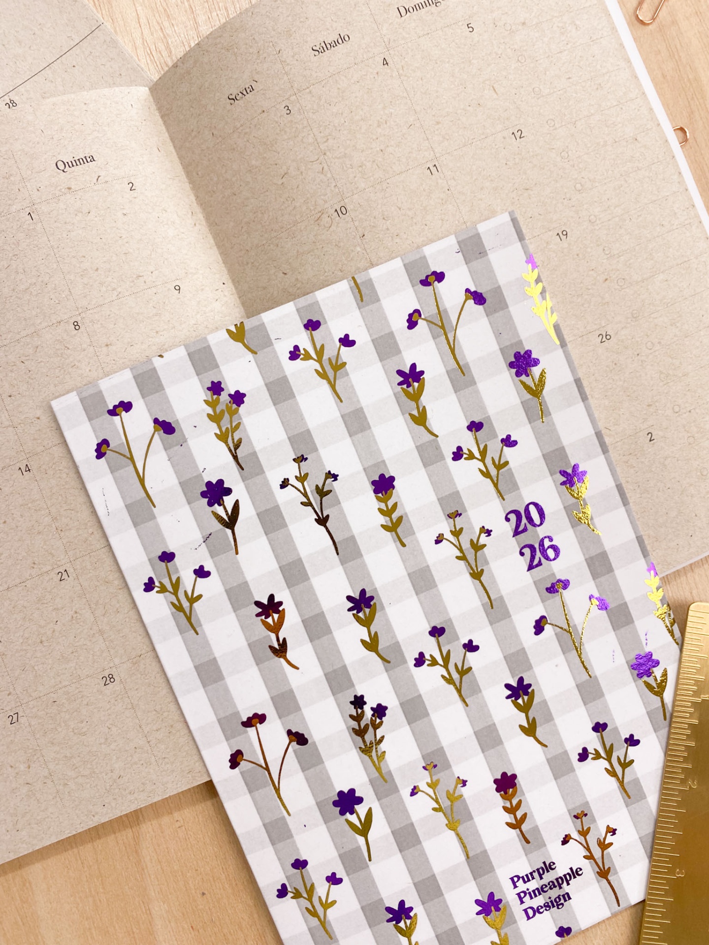 Calendário aberto com caderno floral 2026 em padrão xadrez cinza