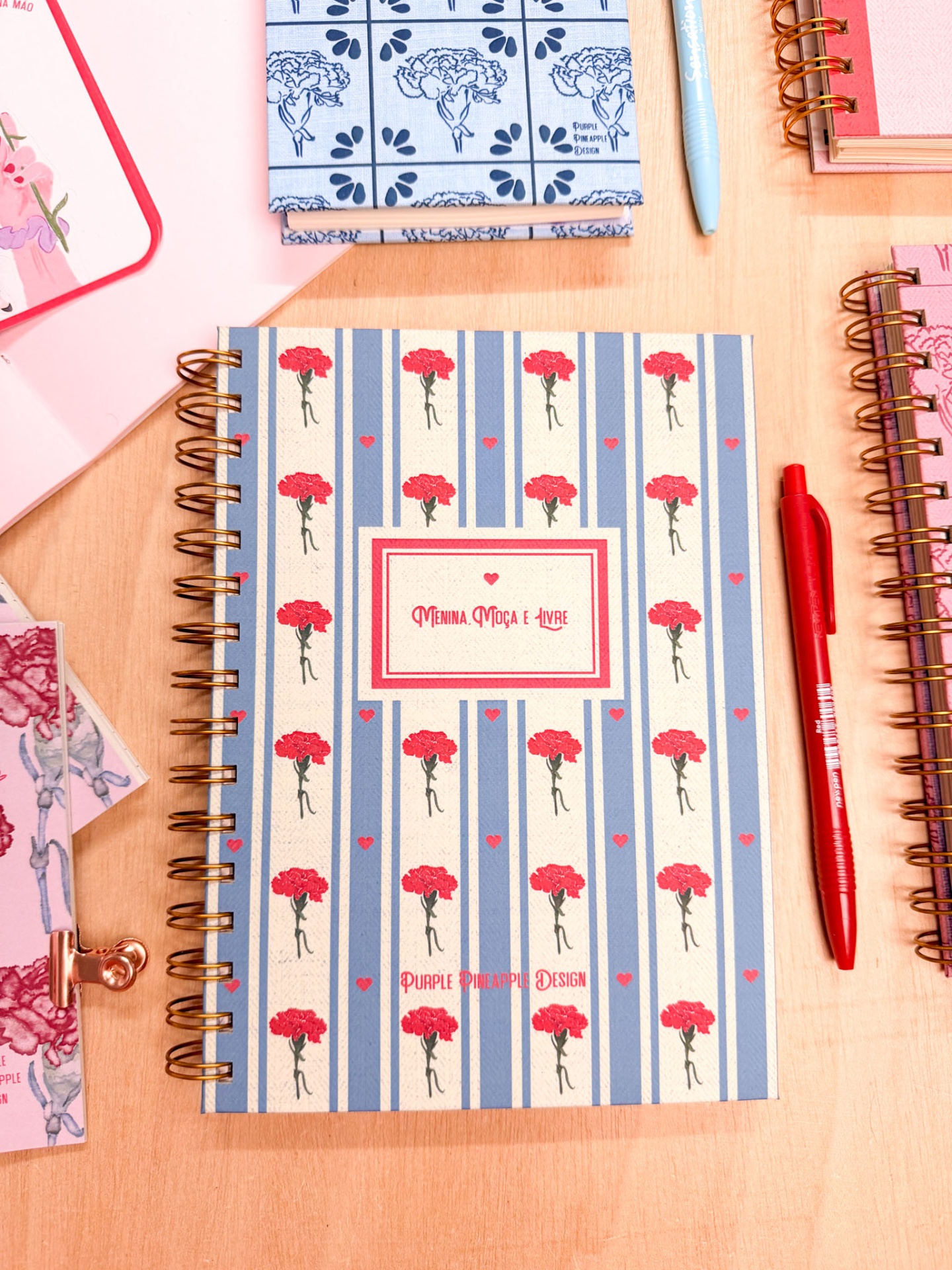 Caderno com capa floral azul e vermelho, espiral dourada