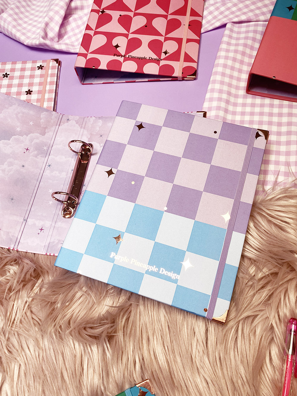 Cadernos e agendas com capas quadriculadas em tons pastel, com texto 'Purple Pineapple Designs'