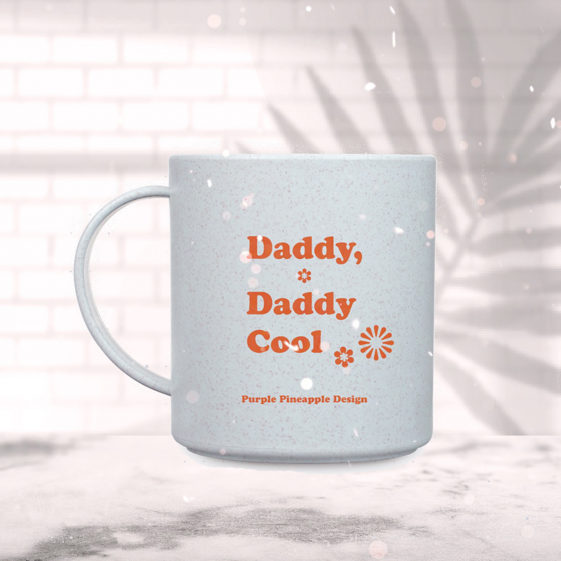 Caneca cinza com texto laranja 'Daddy, Daddy Cool' e flores, sobre superfície clara