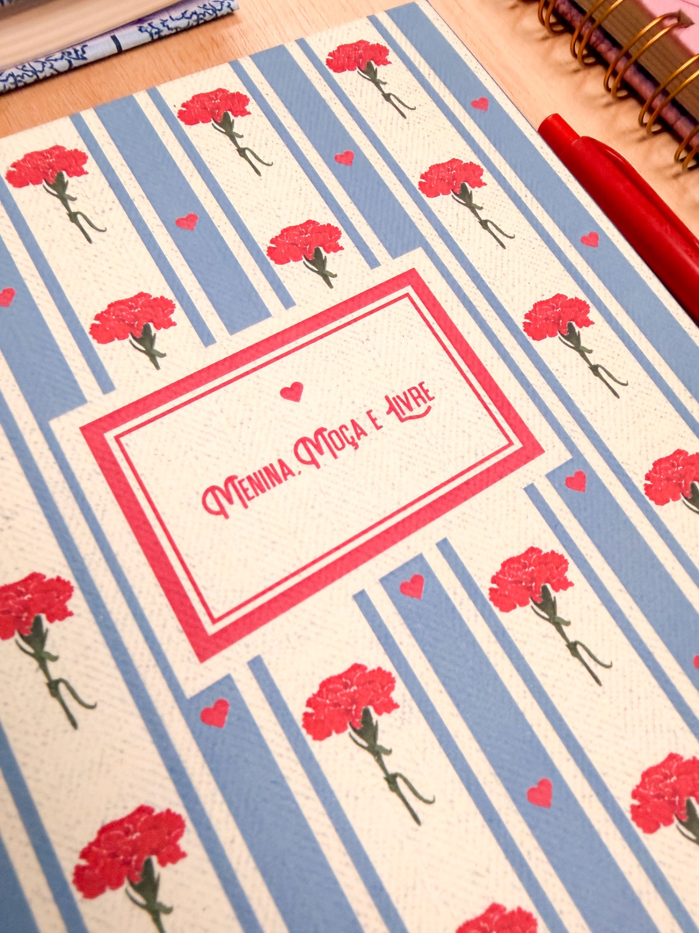 Caderno decorado com flores vermelhas em listras azuis e brancas e texto centralizado