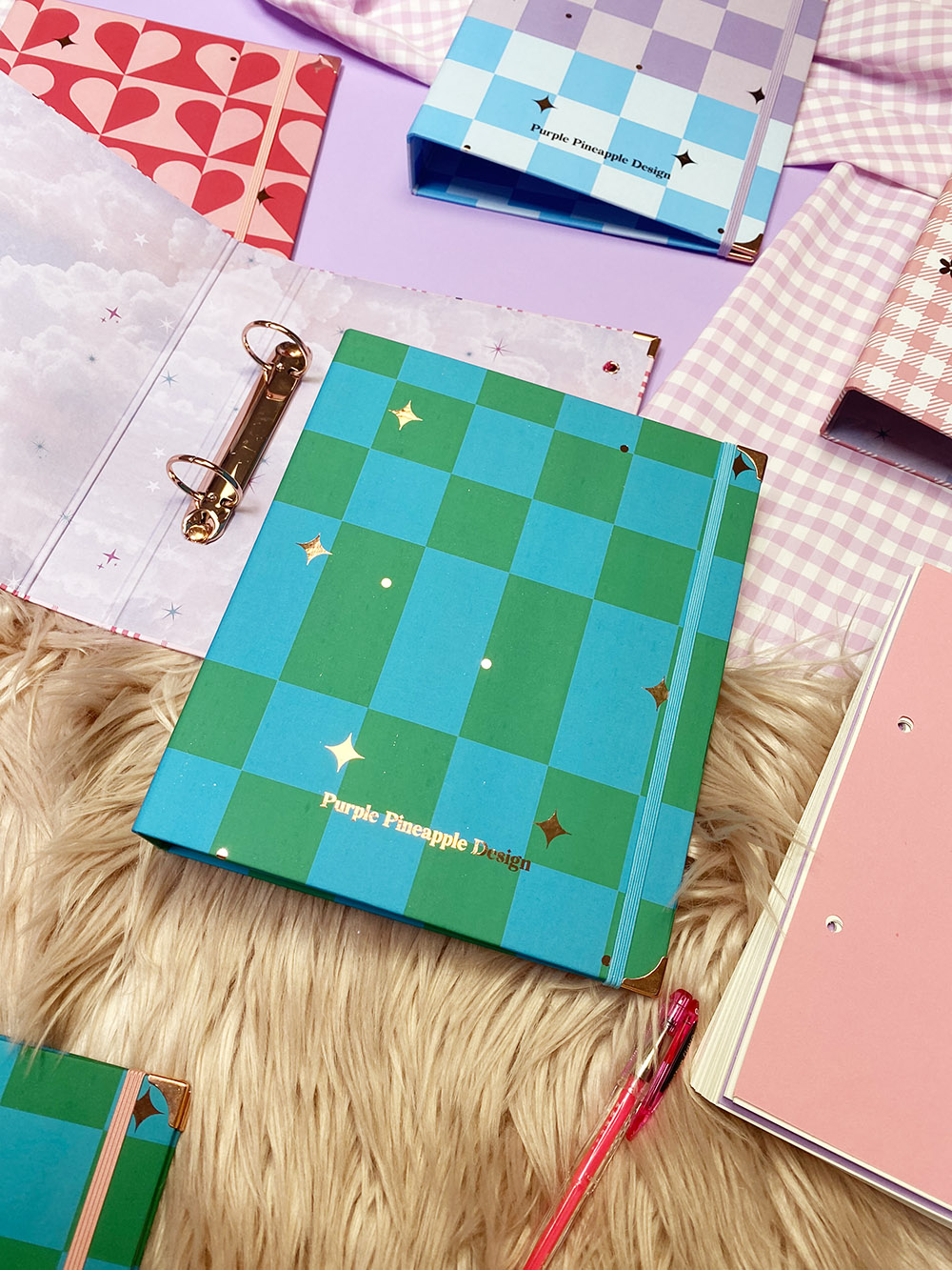 Pasta de argolas verde e azul com padrão quadriculado e estrelas douradas