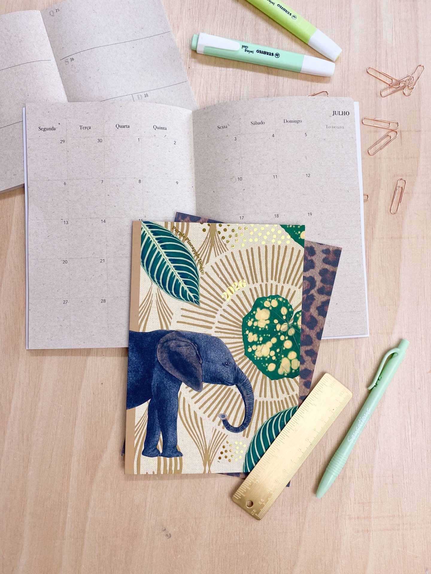 Cadernos, marcadores, clips, régua e caneta sobre mesa clara