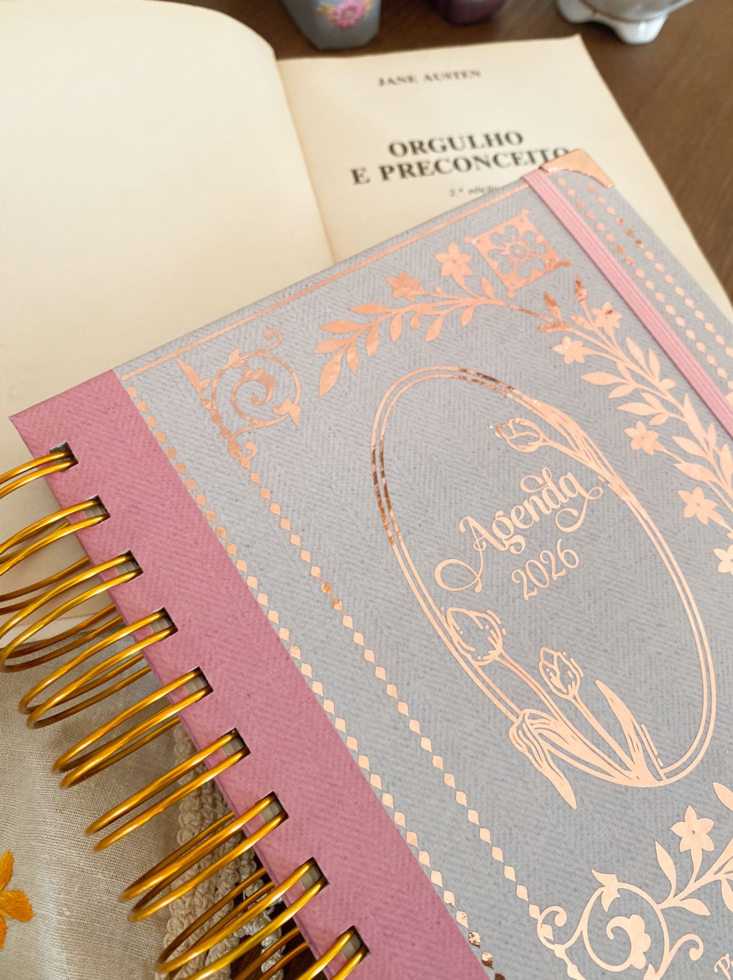 Agenda 2026 com capa cinzenta e rosa com detalhes dourados e elástico rosa