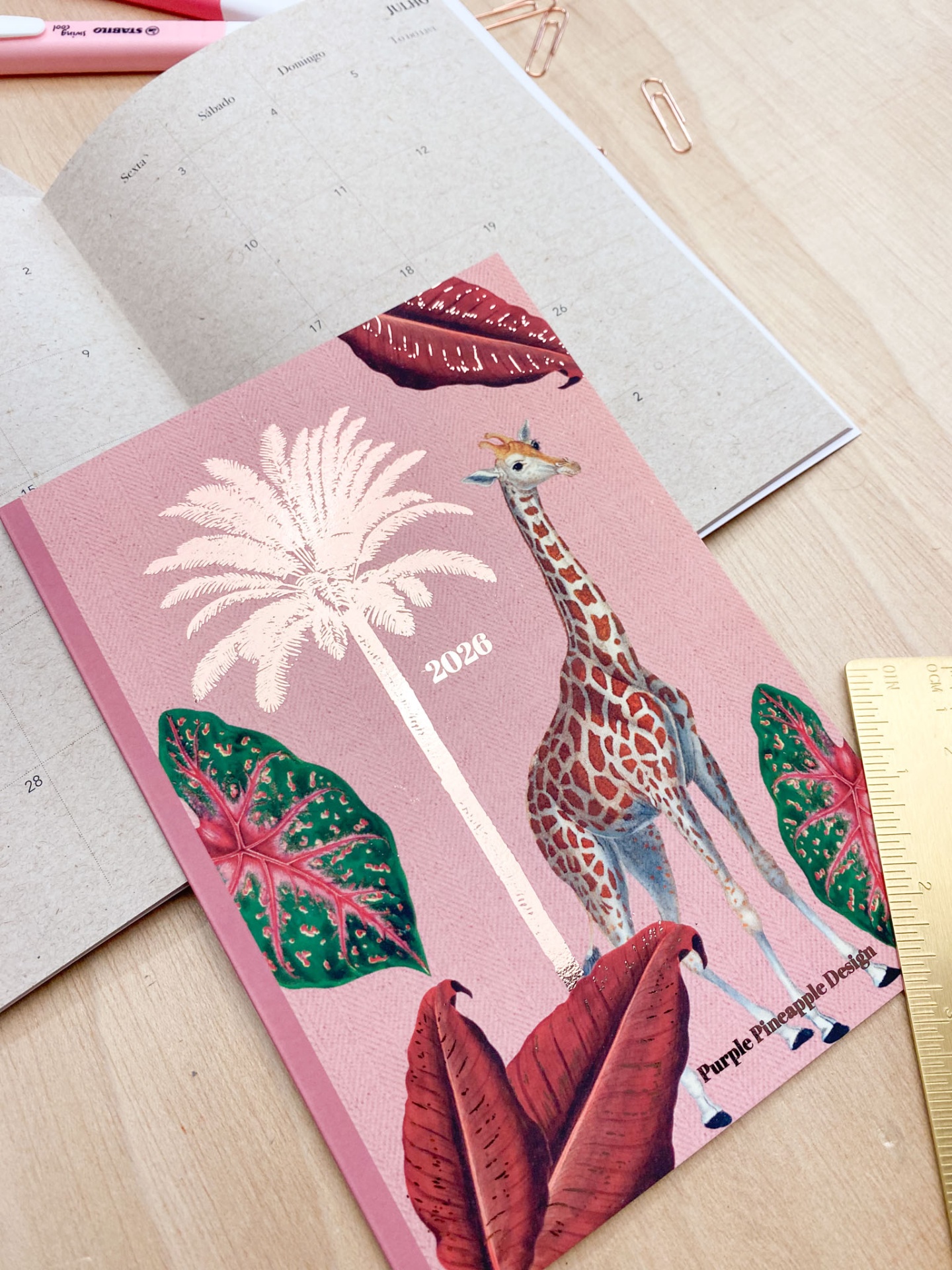 Caderno rosa com ilustração de girafa e folhas tropicais, texto 2020 e Purple Hieroglyphic Design