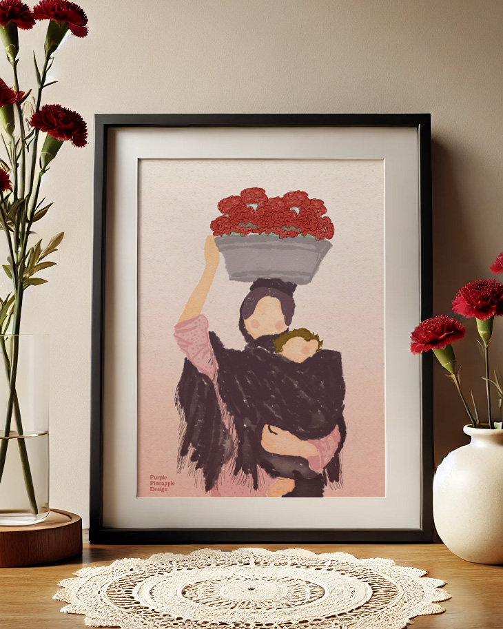 Quadro ilustrativo de pessoa com criança e flores, moldura preta sobre mesa de madeira com vaso e flores vermelhas.