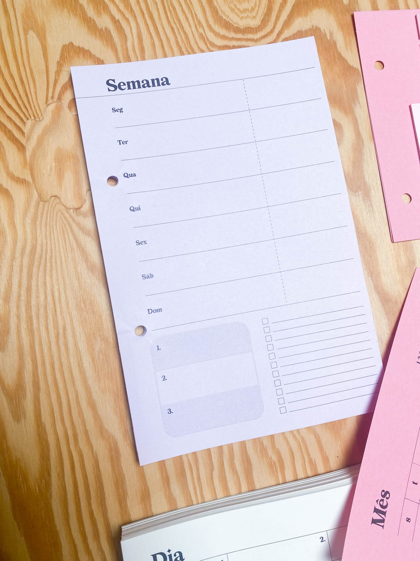 Folha branca de papel para planeamento semanal com dias da semana e caixa de seleção sobre mesa de madeira clara