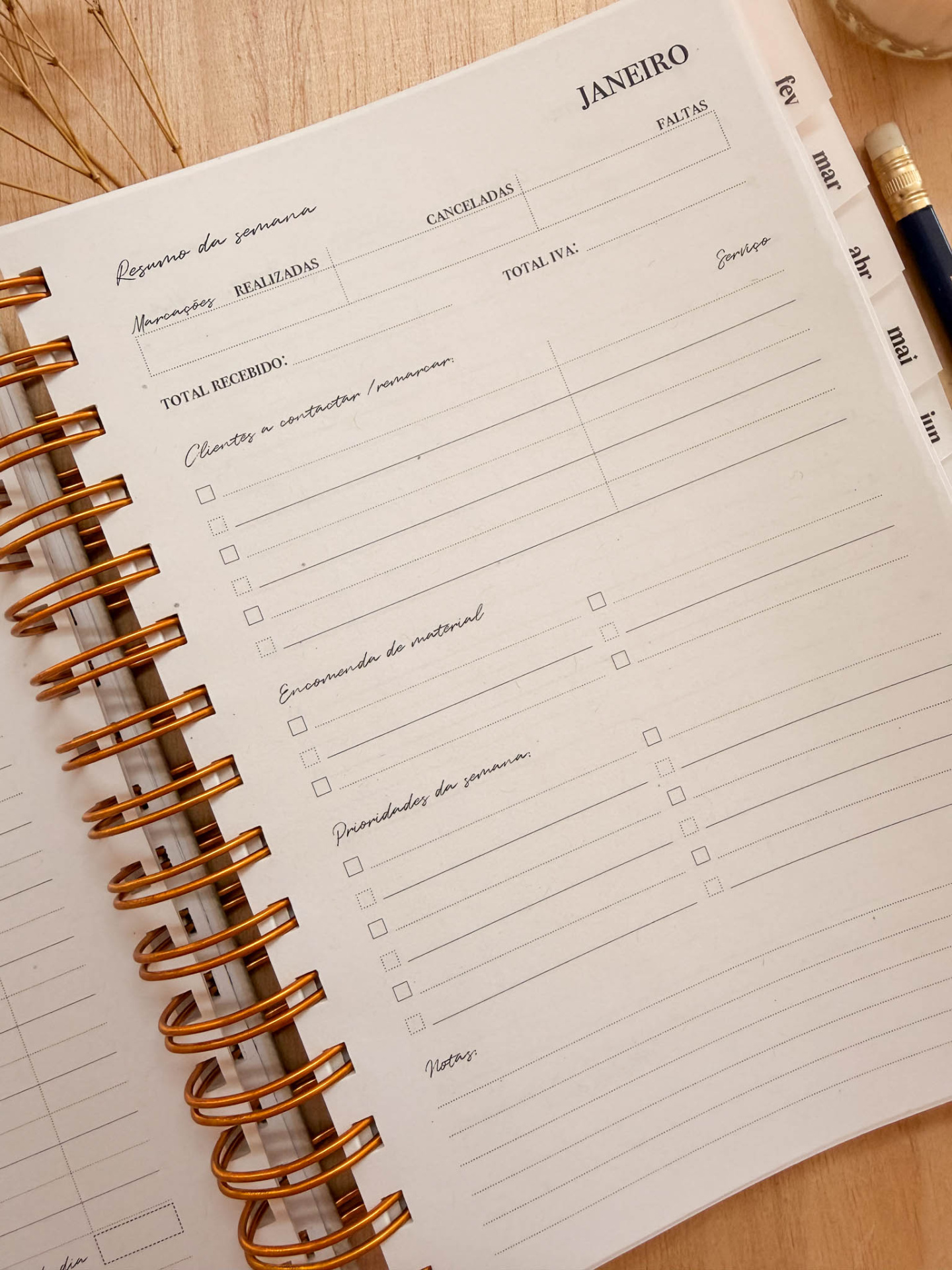Página de caderno ou agenda com layout de resumo da semana, com espiral cobre em fundo de madeira clara.