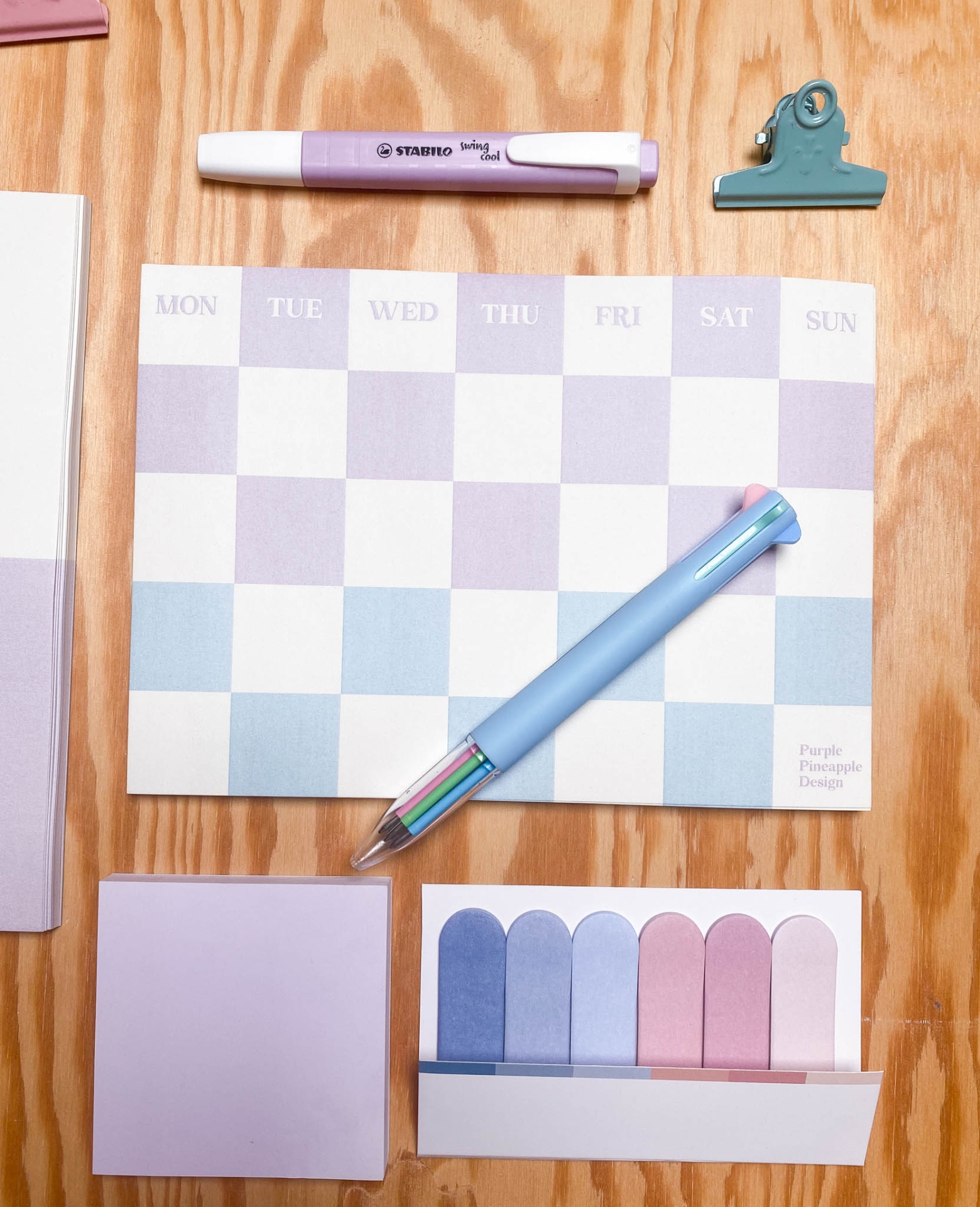 Conjunto de material de escritório em tons pastel sobre mesa de madeira