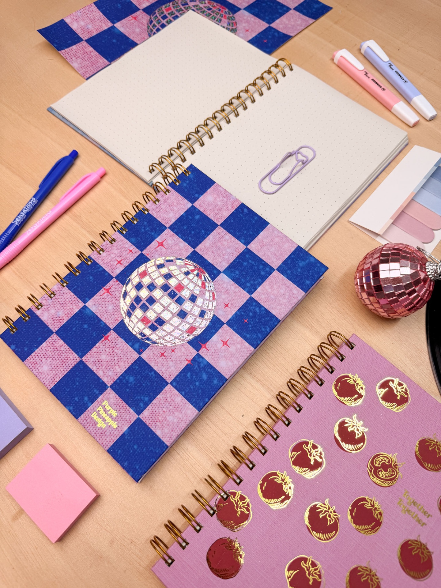 Dois cadernos espirais coloridos sobre mesa com material de escritório