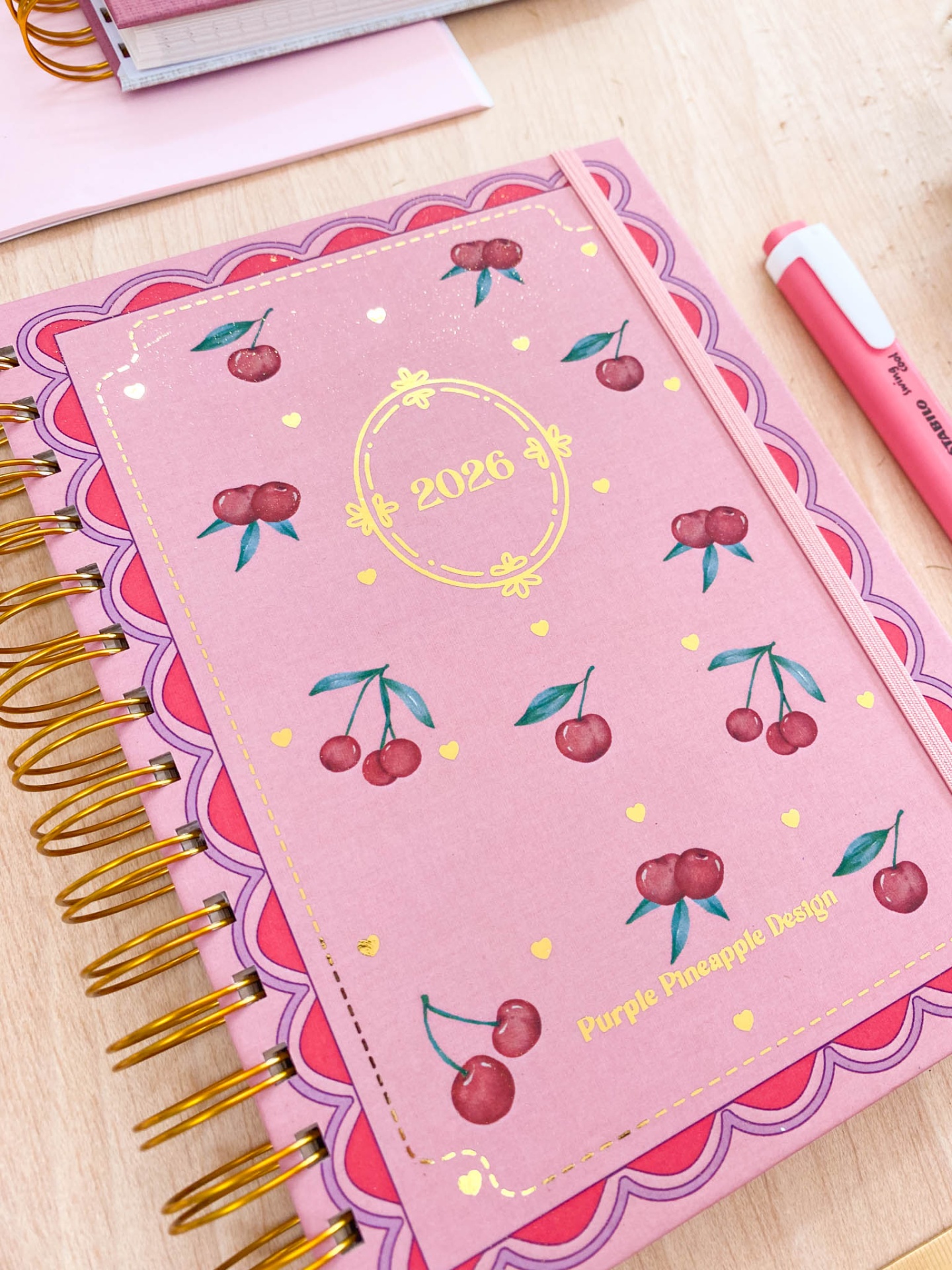 Agenda 2026 rosa com padrão de cerejas e detalhes dourados