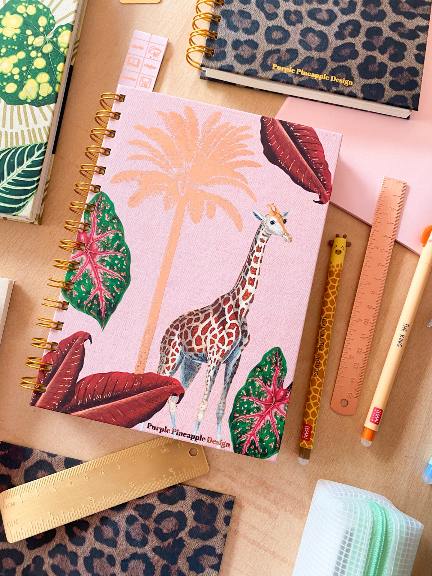 Caderno espiral rosa com ilustração de girafa e folhas tropicais