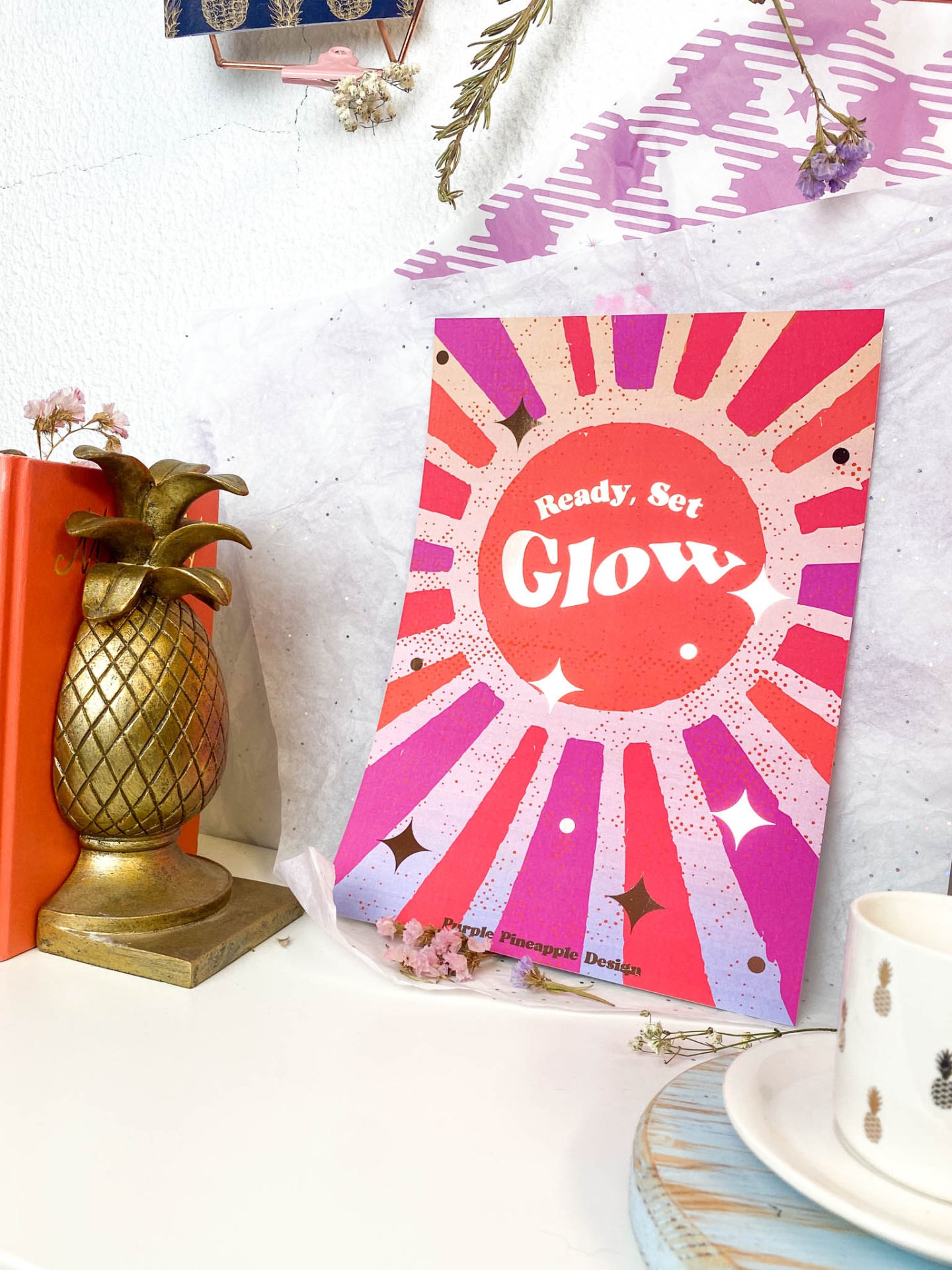 Cartaz colorido com texto 'Ready, Set Glow' numa mesa com decoração diversificada