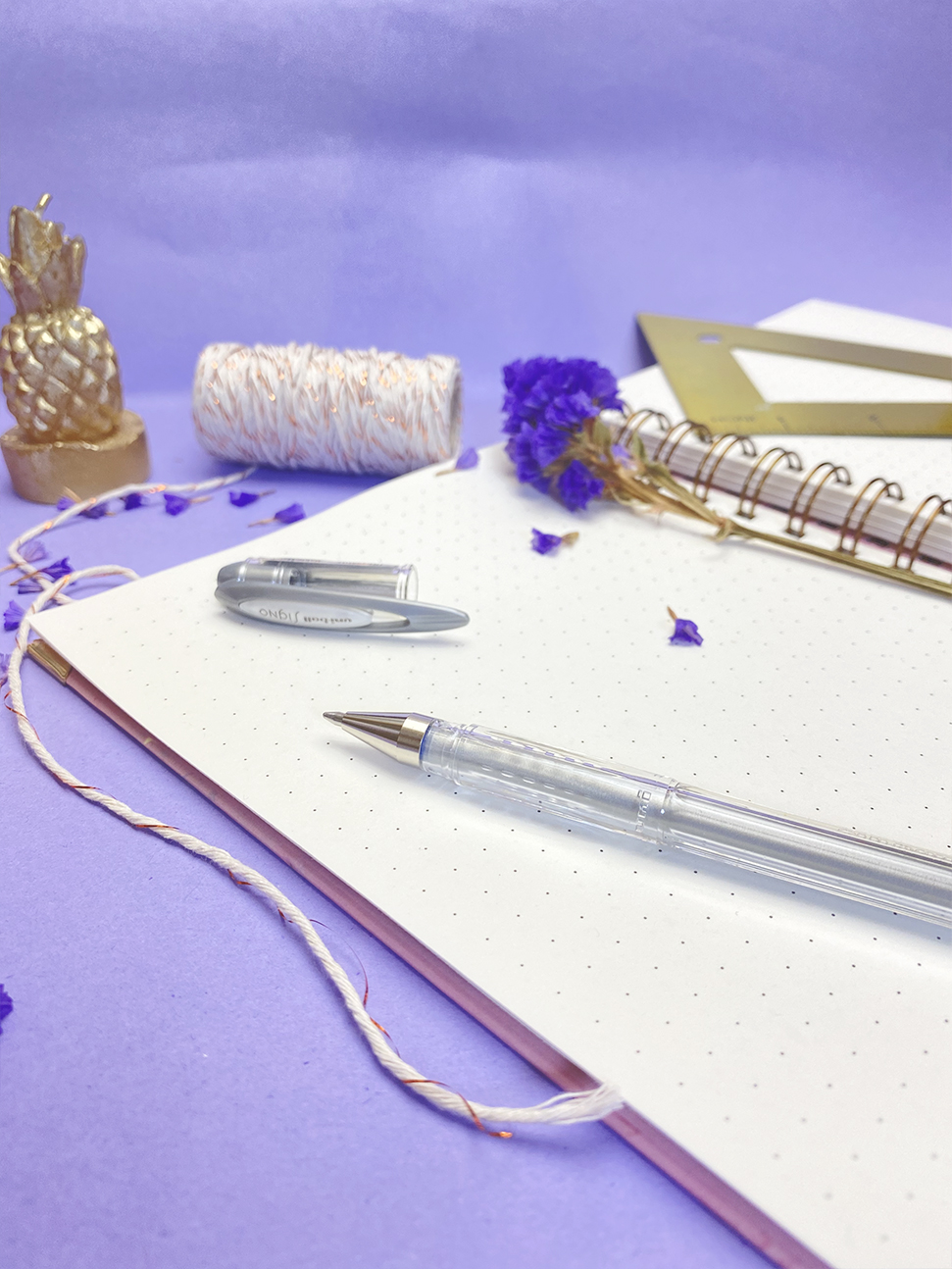 Caderno espiral pontilhado, caneta transparente, cordão e flores secas roxas com decoração e rolo de fio