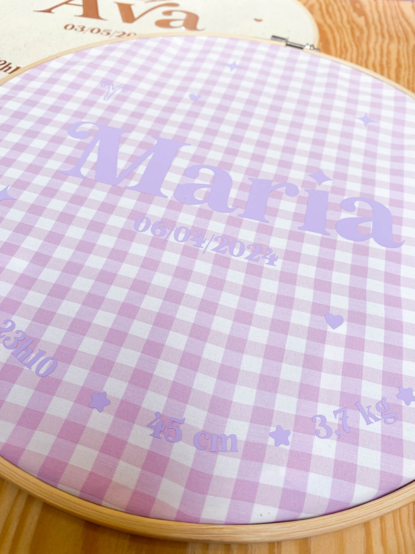 Arco de bordado com tecido xadrez violeta e branco com texto impresso 'Maria' e datas