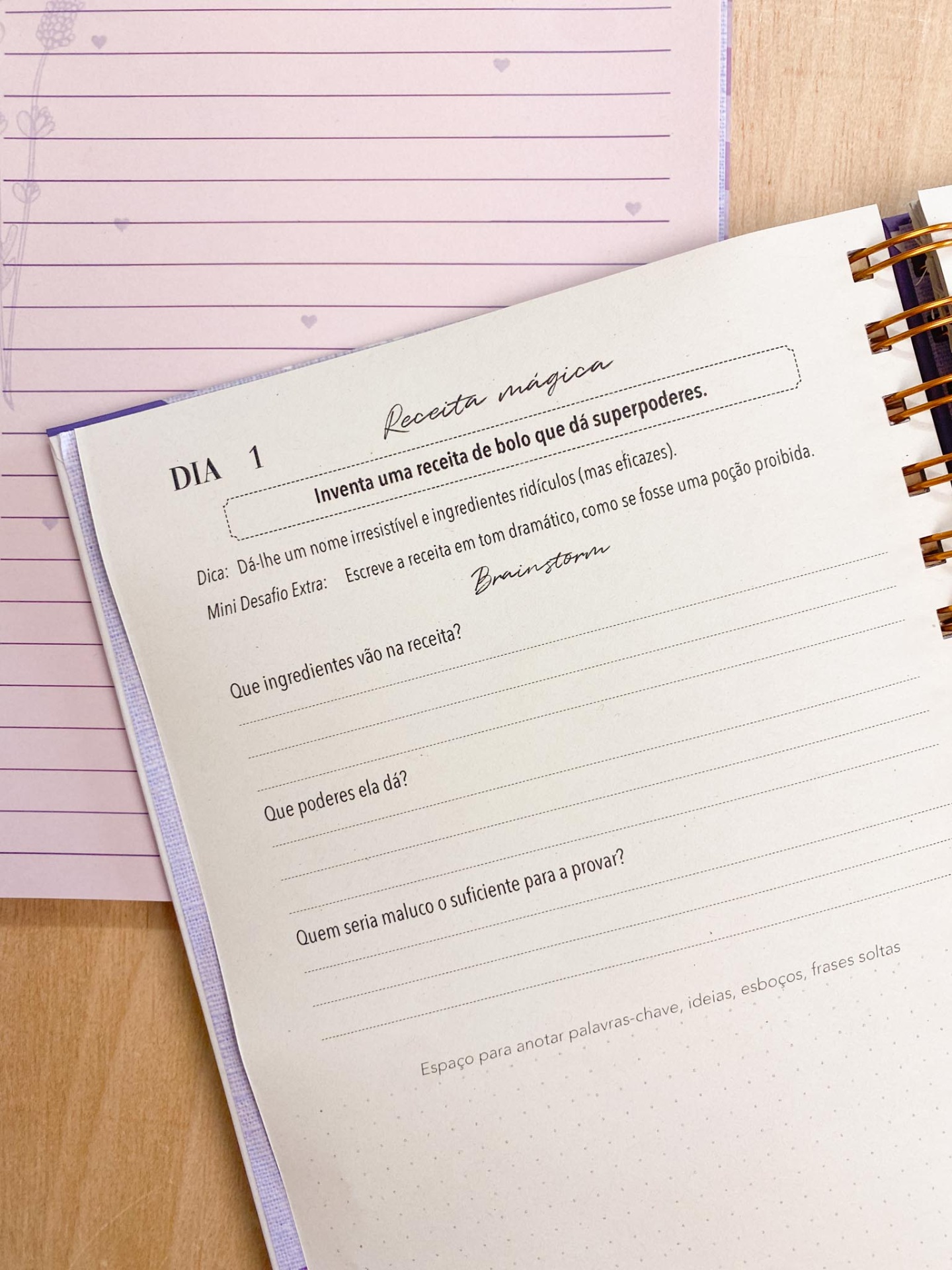 Caderno aberto com texto em português sobre receita mágica, com anel dourado, sobre mesa de madeira