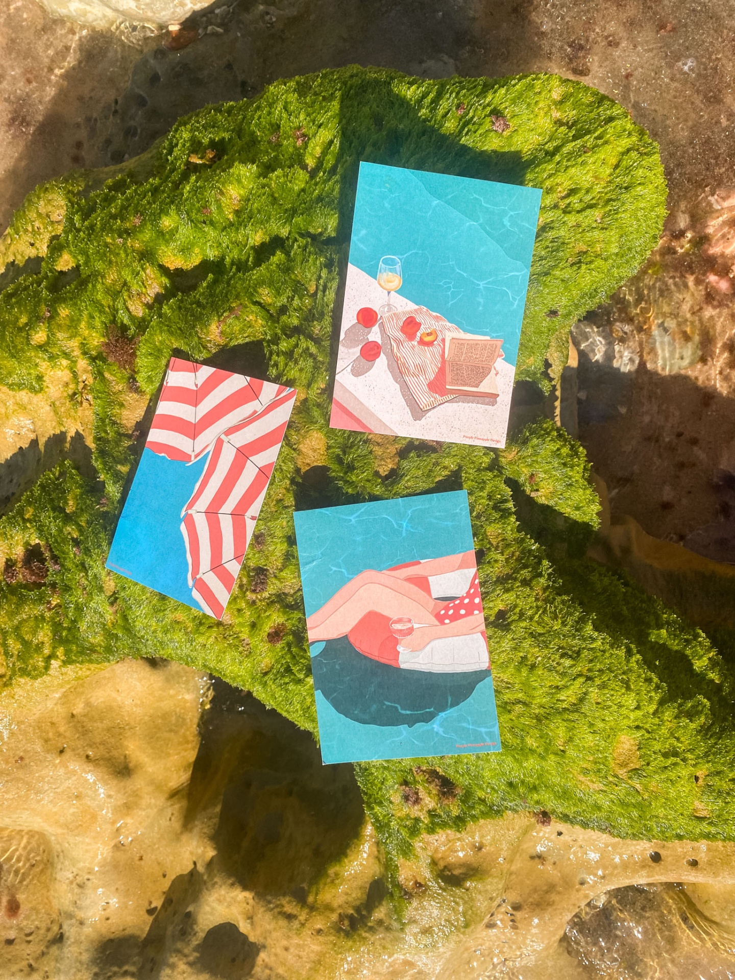 Três postais com ilustrações de praia e piscina sobre pedra verde