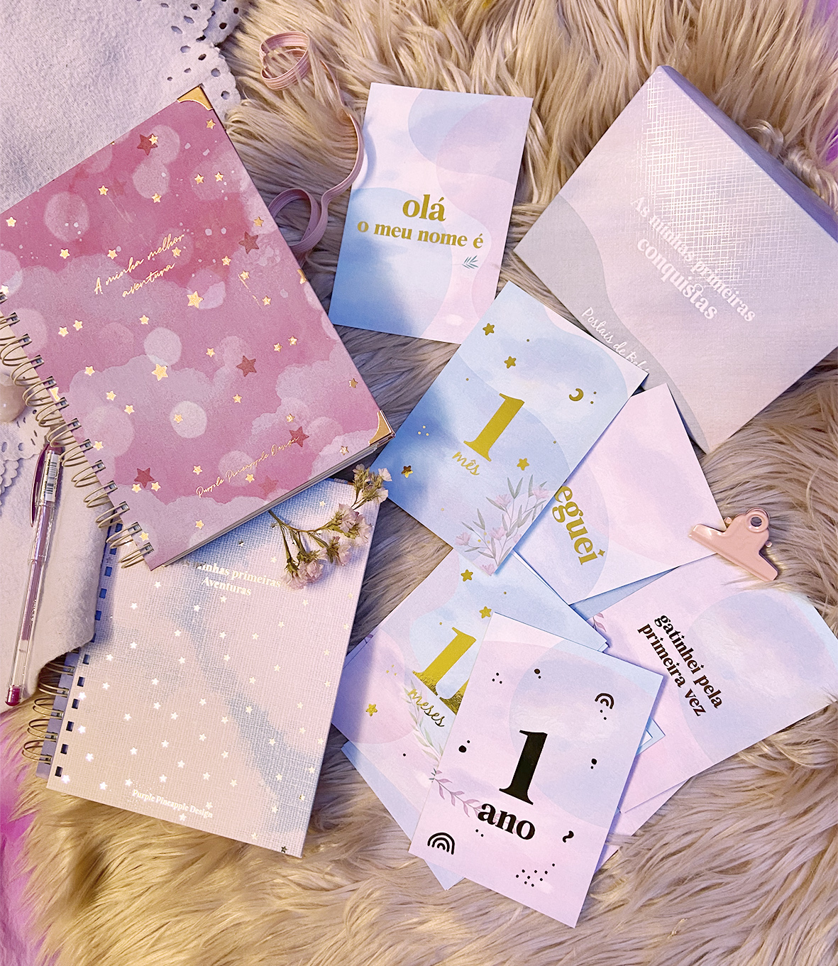 Caderno rosa com estrelas, cartões coloridos com textos em português sobre tapete peludo bege.