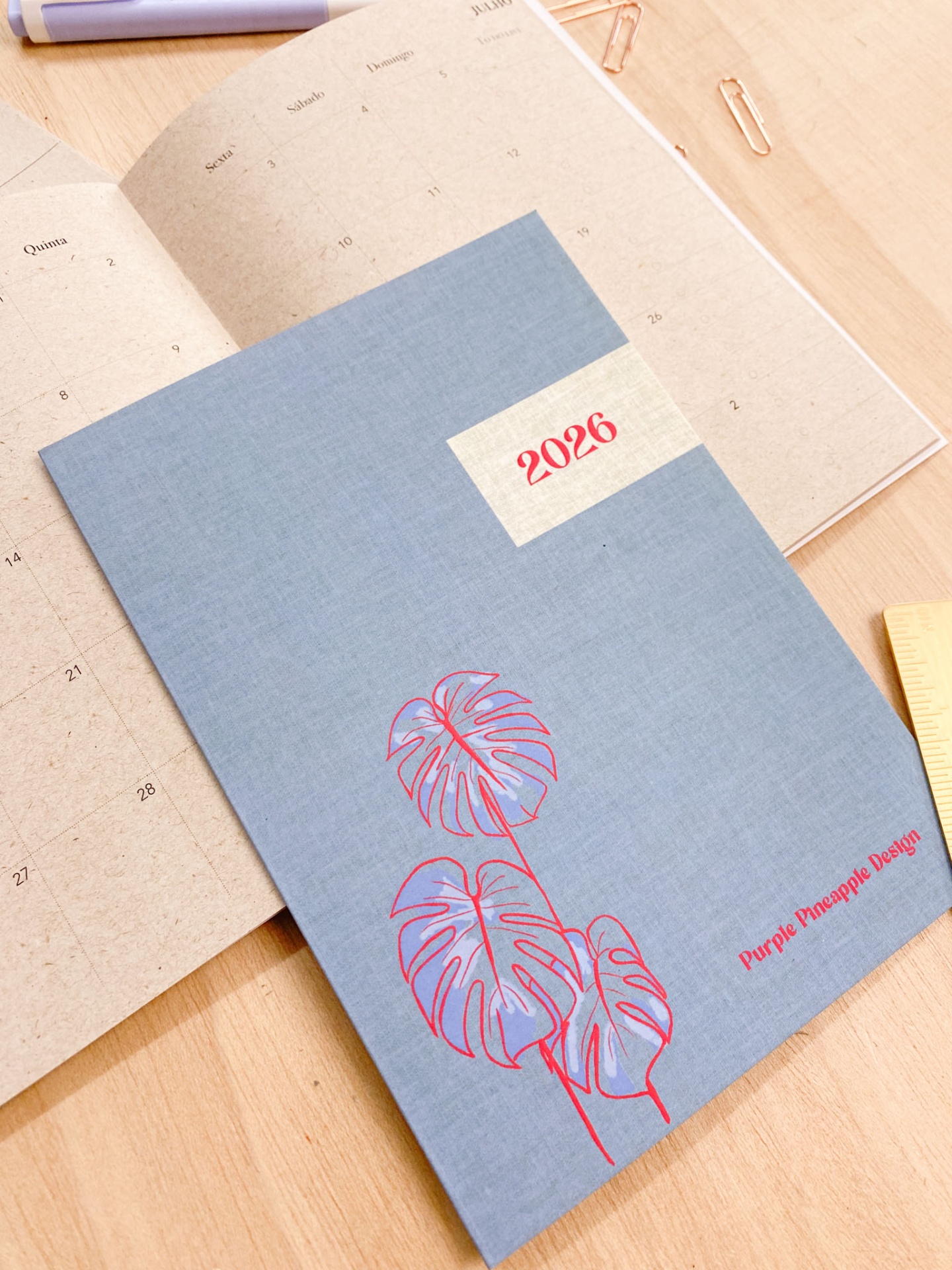 Agenda azul com folhas vermelhas e texto '2026' e 'Purple Pineapple Design'