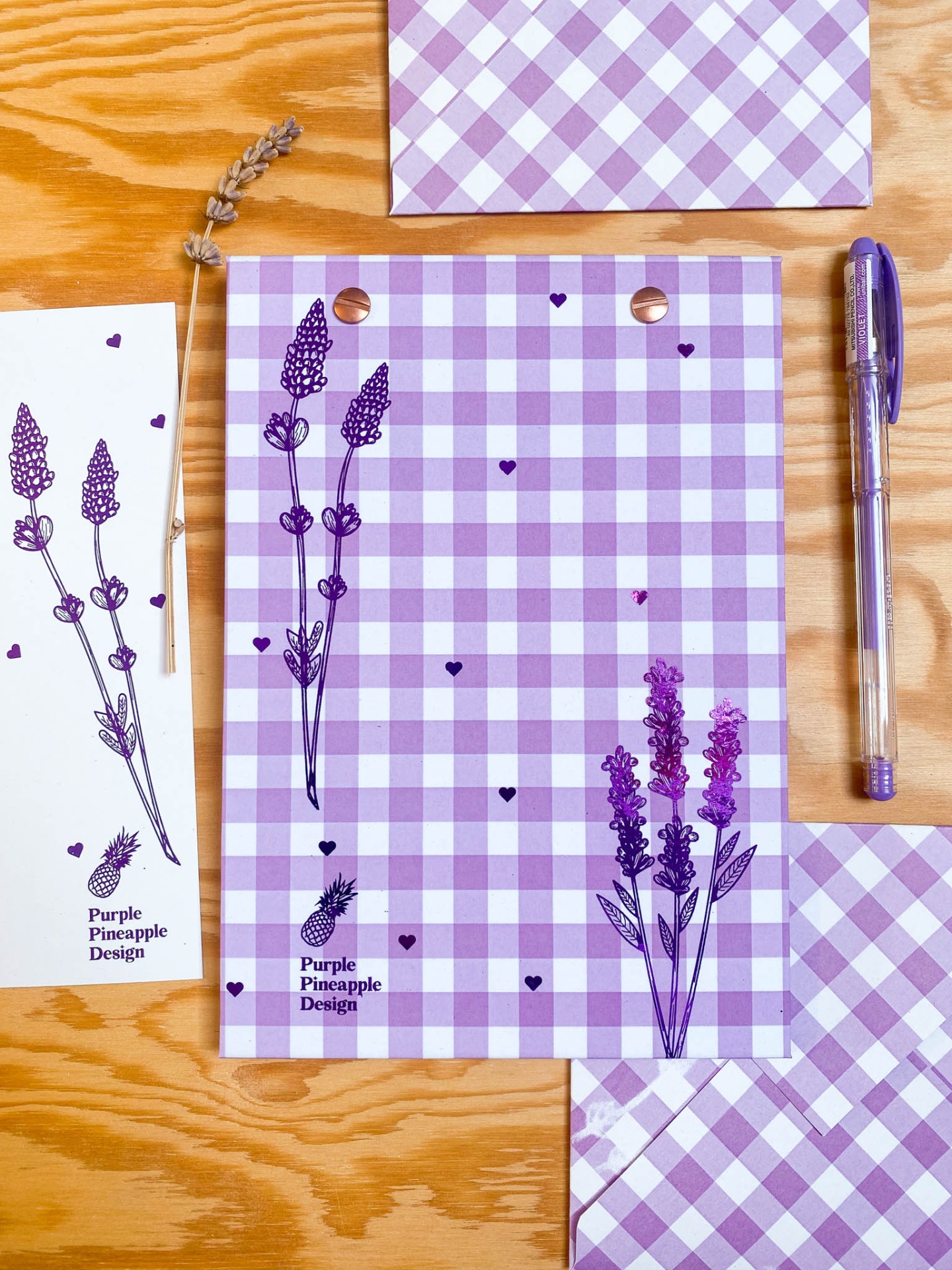 Material de papelaria com padrão xadrez lilás, ilustrações de lavanda e texto Purple Pineapple Design