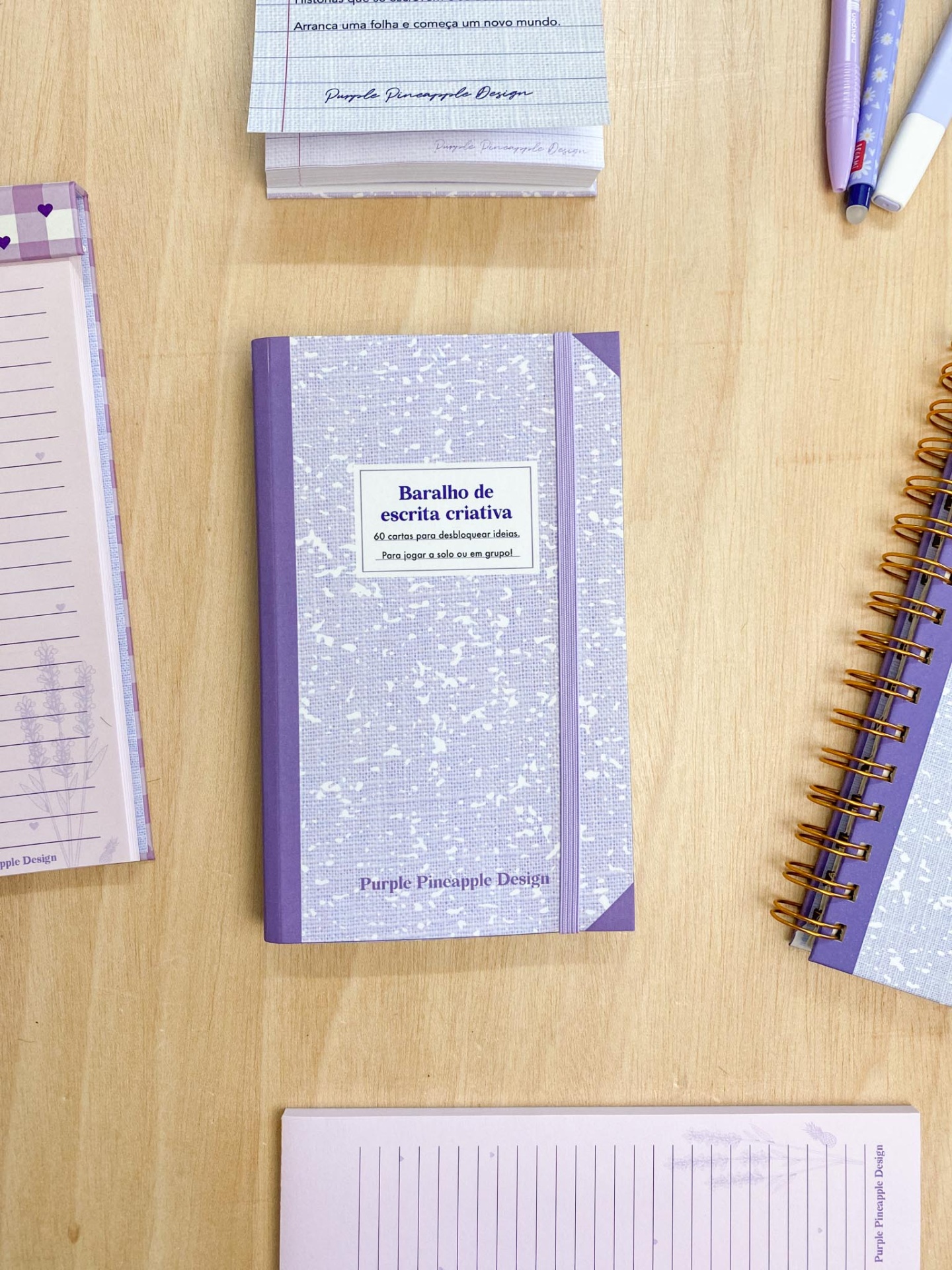 Caderno lilás com elástico e texto 