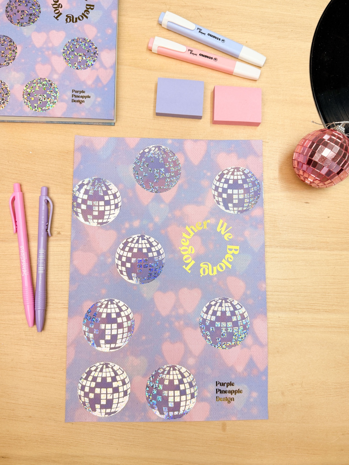 Papel decorativo com design holográfico azul-púrpura com canetas e blocos de notas sobre mesa de madeira clara