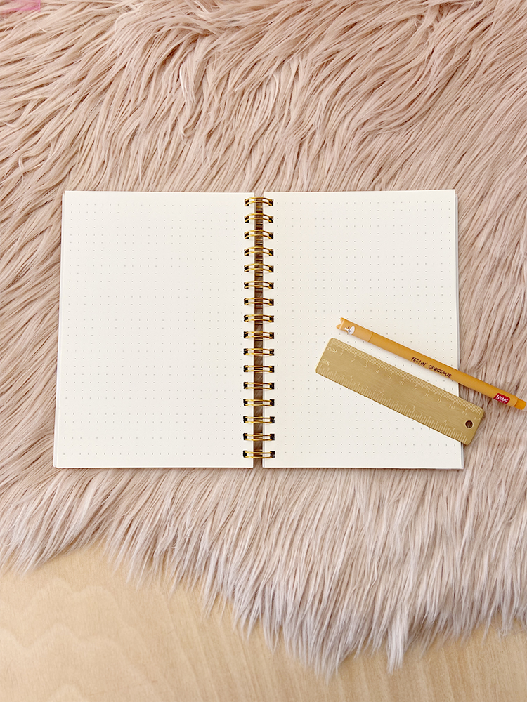 Caderno aberto com régua e lápis sobre superfície felpuda rosa