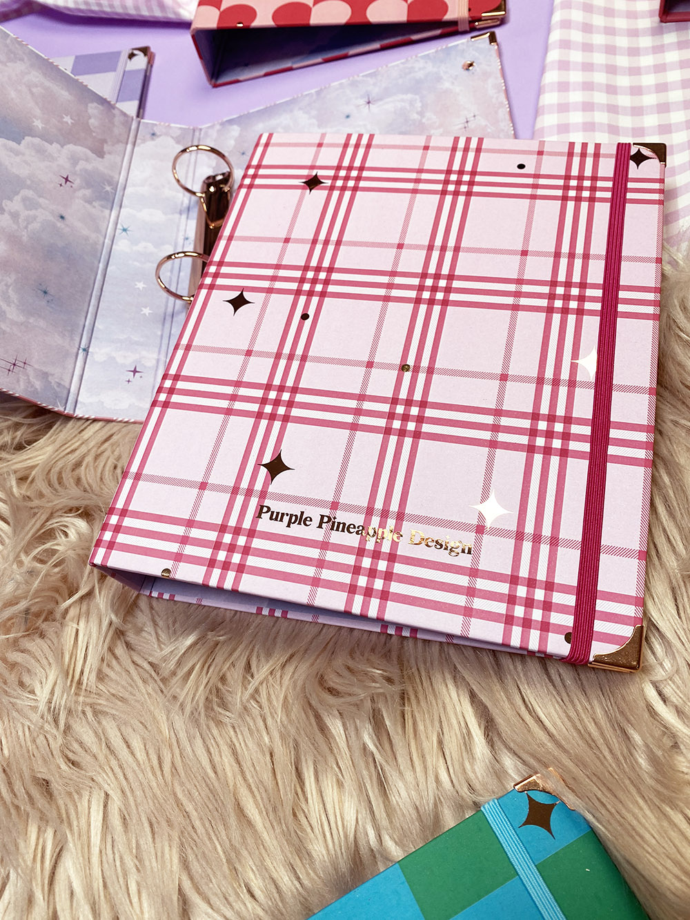 Caderno com capa quadriculada rosa e branca e texto em dourado