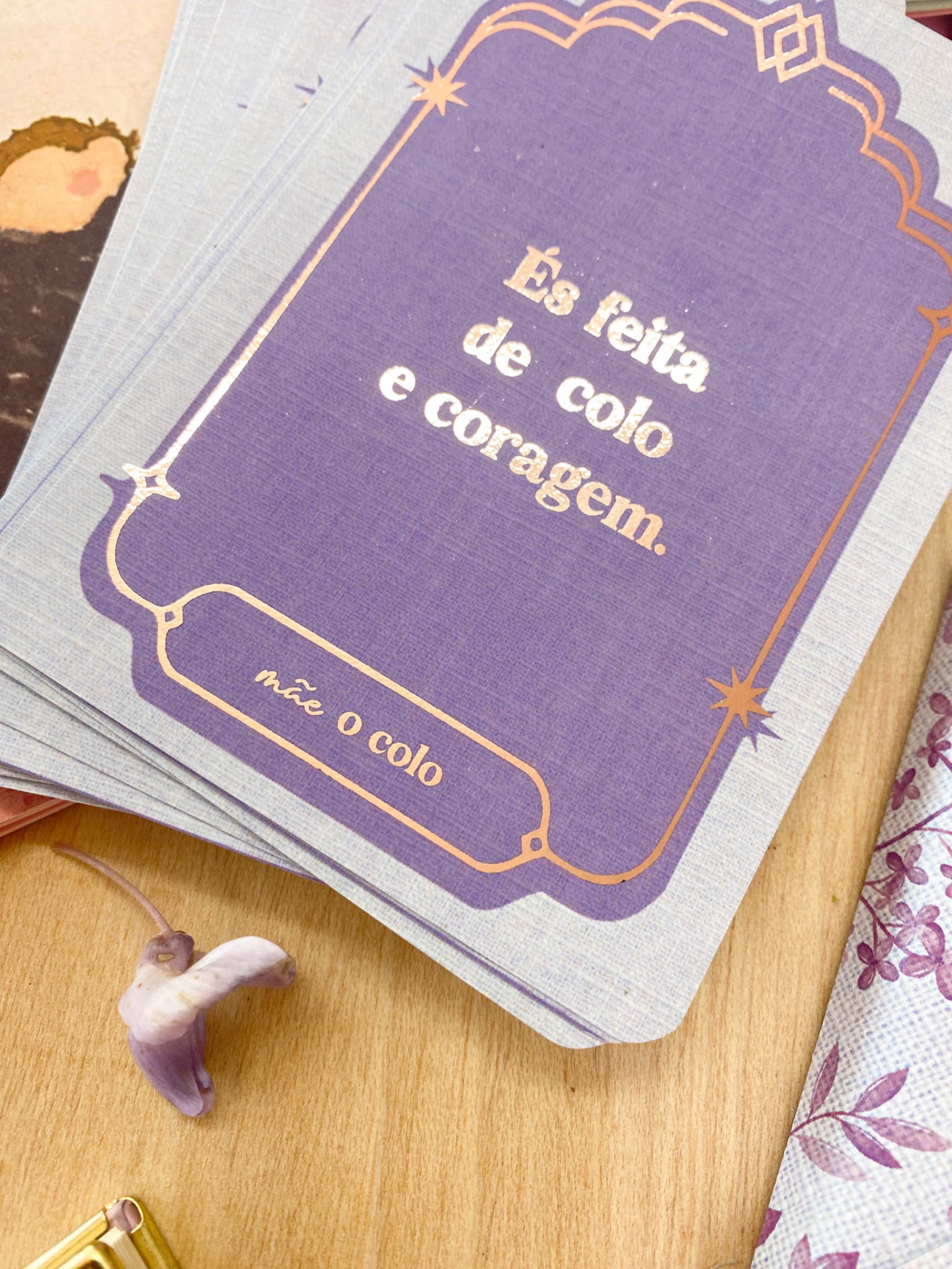 Cartas com texto motivacional em fundo lilás sobre madeira com pequeno objeto roxo ao lado