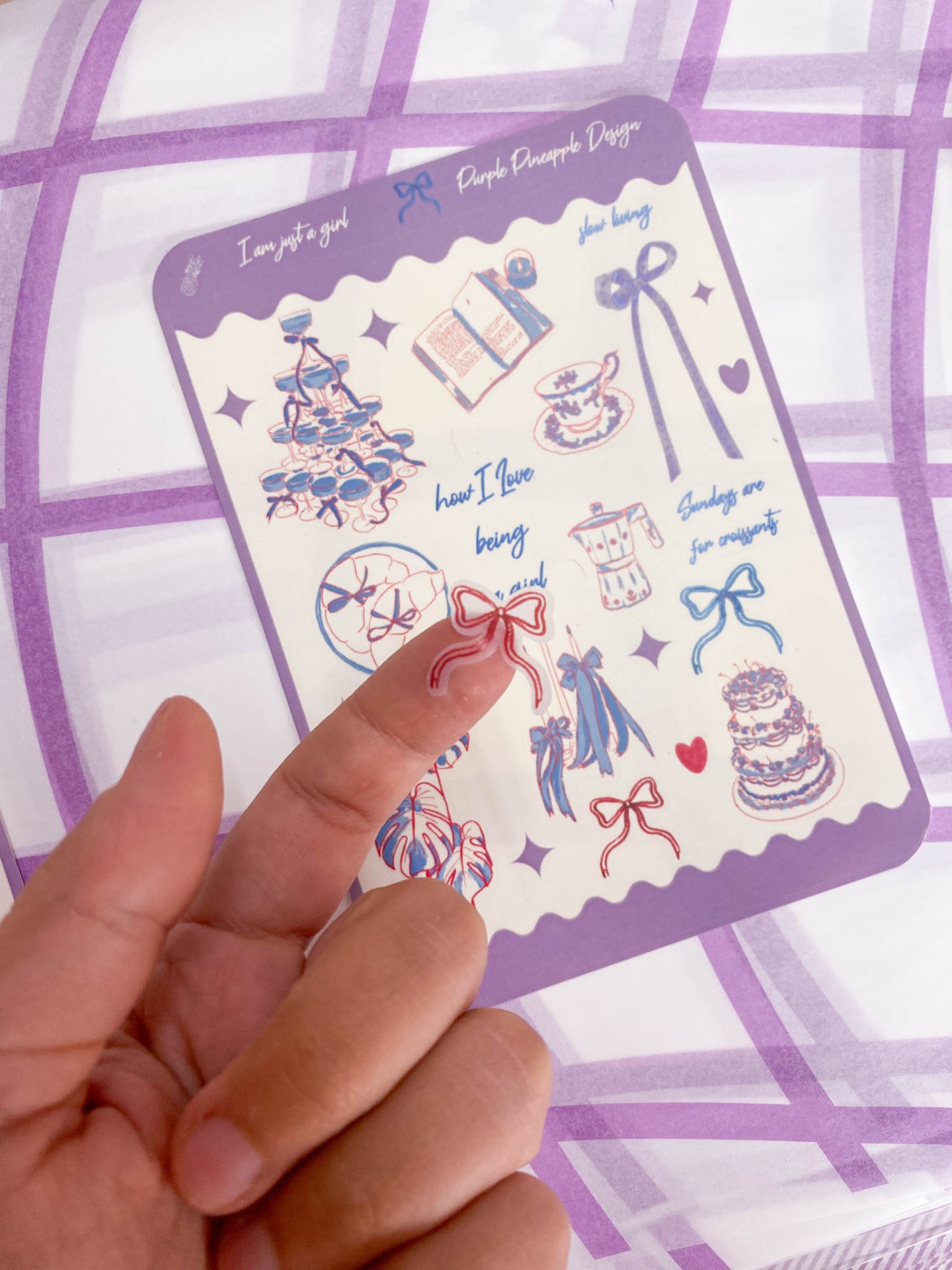 Folha de autocolantes com desenhos de lacinhos, vestidos, bolos e chávenas em cores azul, rosa e roxo.