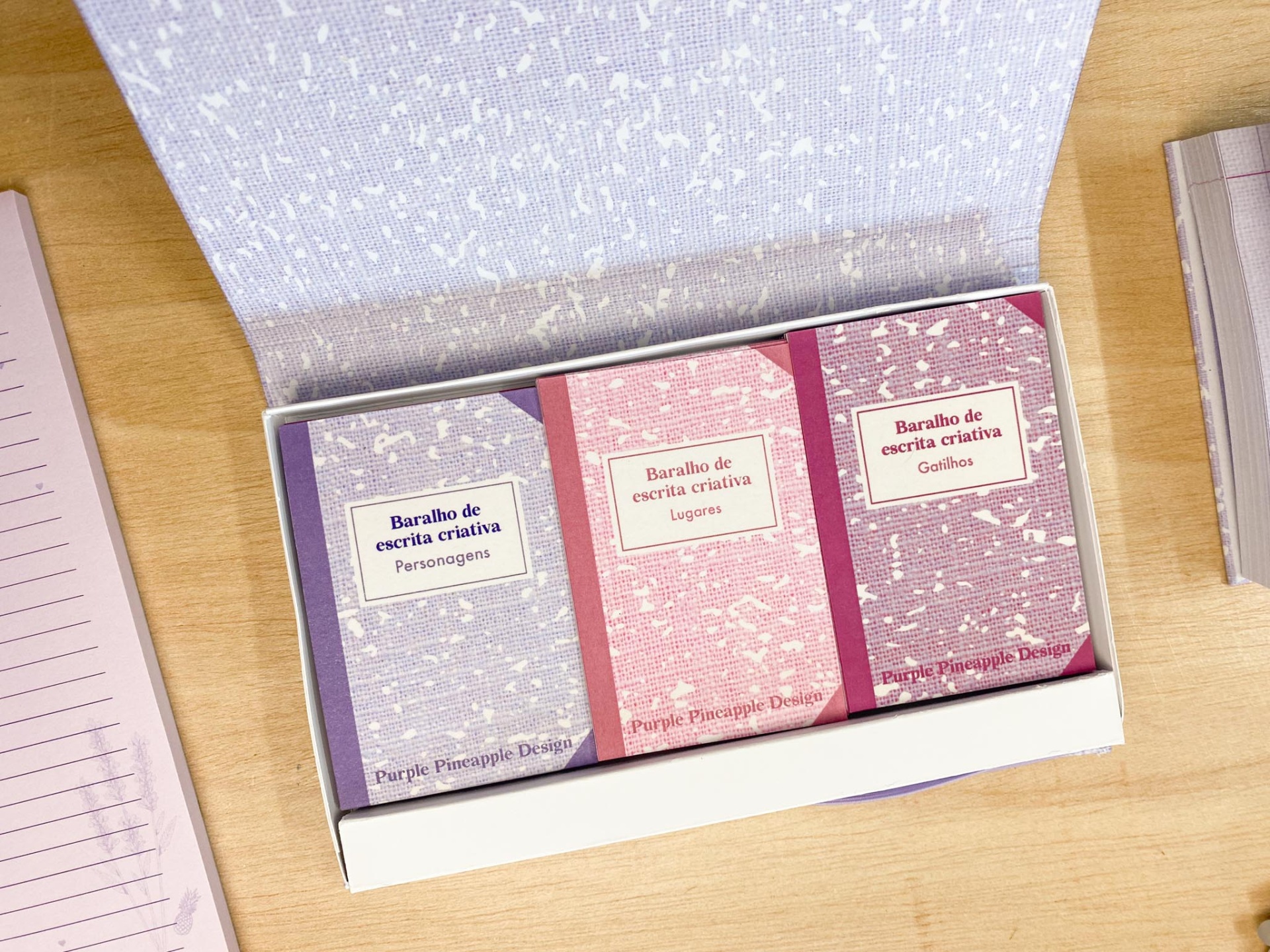 Três blocos de notas coloridos numa caixa branca aberta.