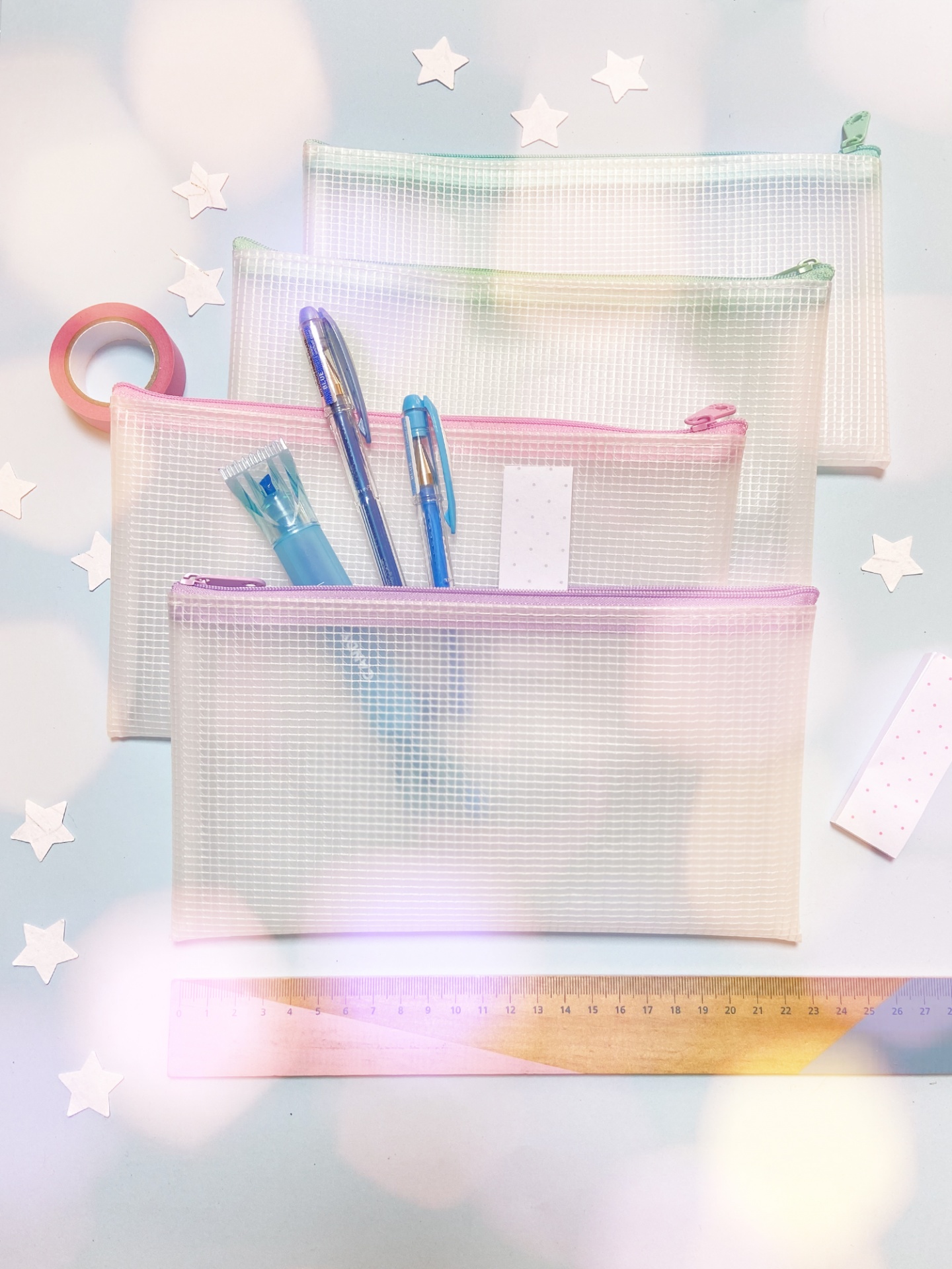 Bolsas organizadoras transparentes com fecho de correr em cores pastel contendo canetas e acessórios de escritório