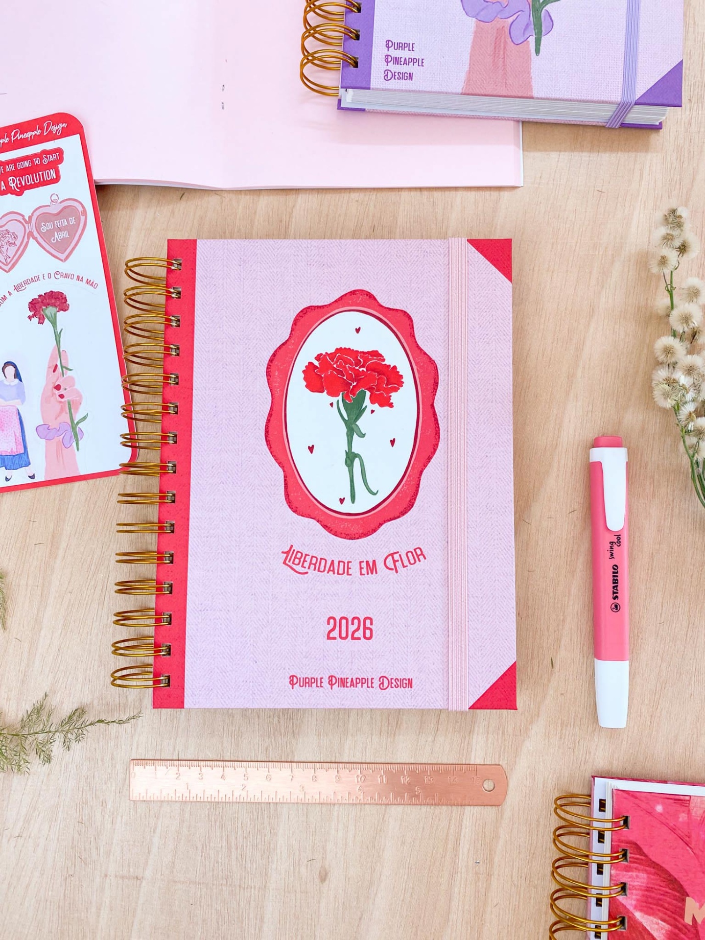 Agenda rosa e vermelha com flor vermelha e texto LIBERDADE EM FLOR 2026