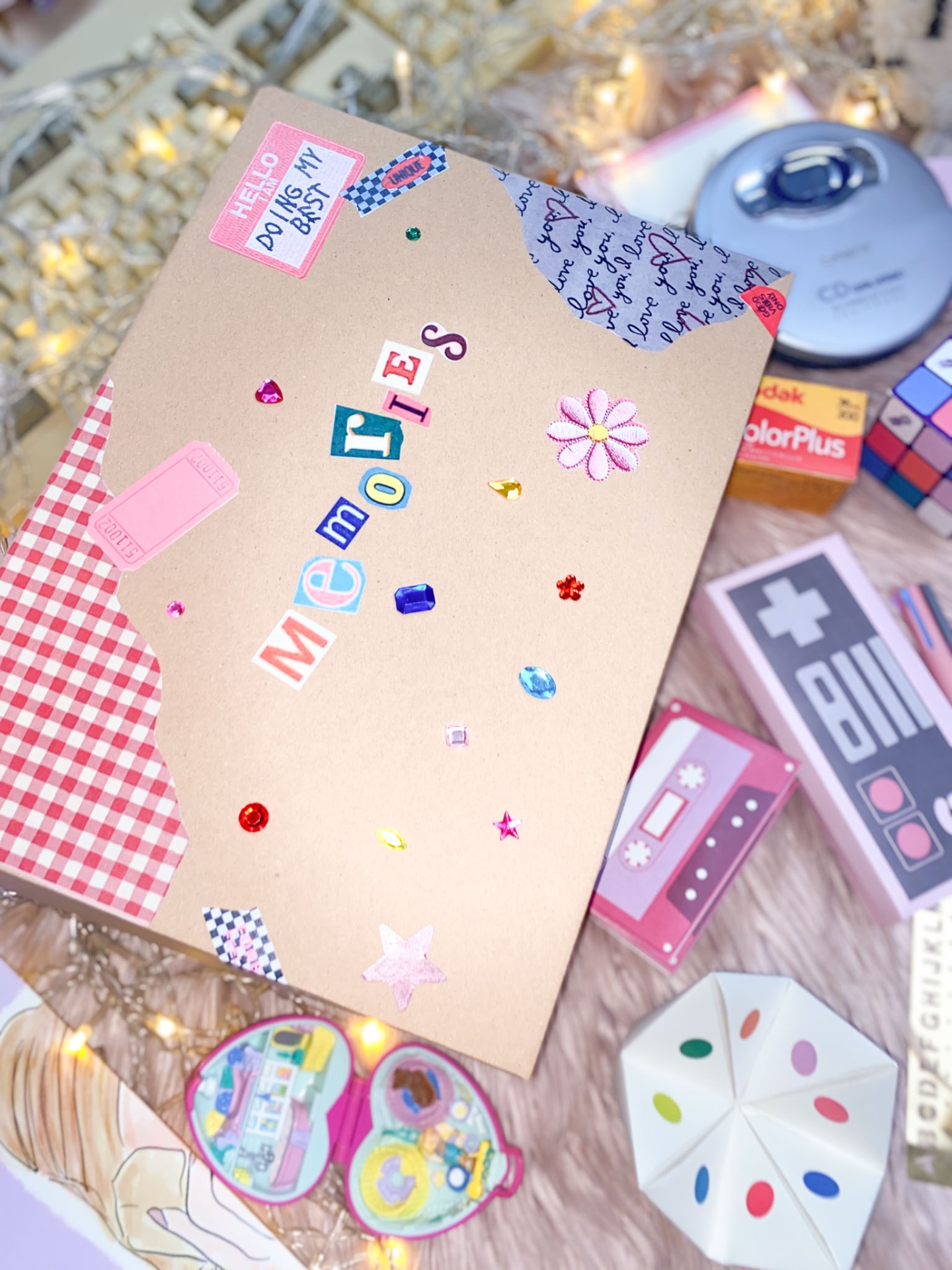 Caderno decorado com colagens, adesivos e pedras coloridas sobre um fundo com objetos vintage e luzes