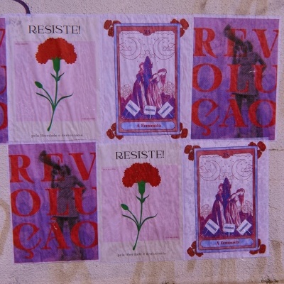 Coleção de cartazes coloridos na parede com mensagens de resistência e revolução.