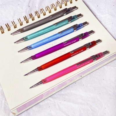 Seis canetas mecânicas coloridas alinhadas em caderno espiral aberto