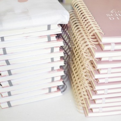 Duas pilhas de cadernos espirais empilhados em cores branco e rosa claro