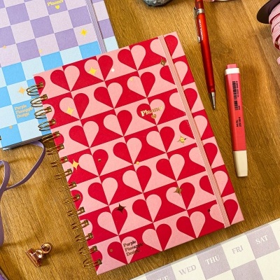 Planners coloridos, caneta, marcador e calendário sobre mesa de madeira