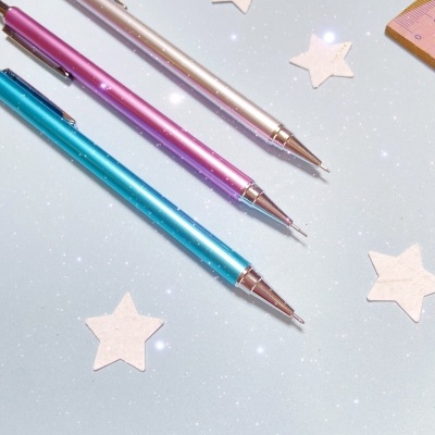 Três lápis mecânicos metálicos coloridos e estrelas de papel