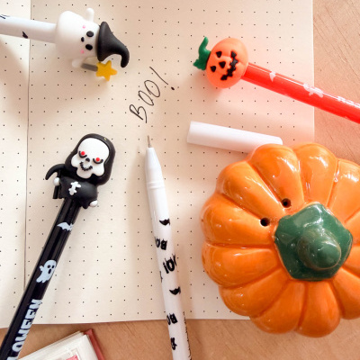 Canetas decorativas de Halloween e abóbora de cerâmica sobre caderno de pontos numa mesa