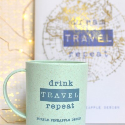 Caneca verde com texto azul e fundo branco com mapa dourado e luzes de fada amarelas